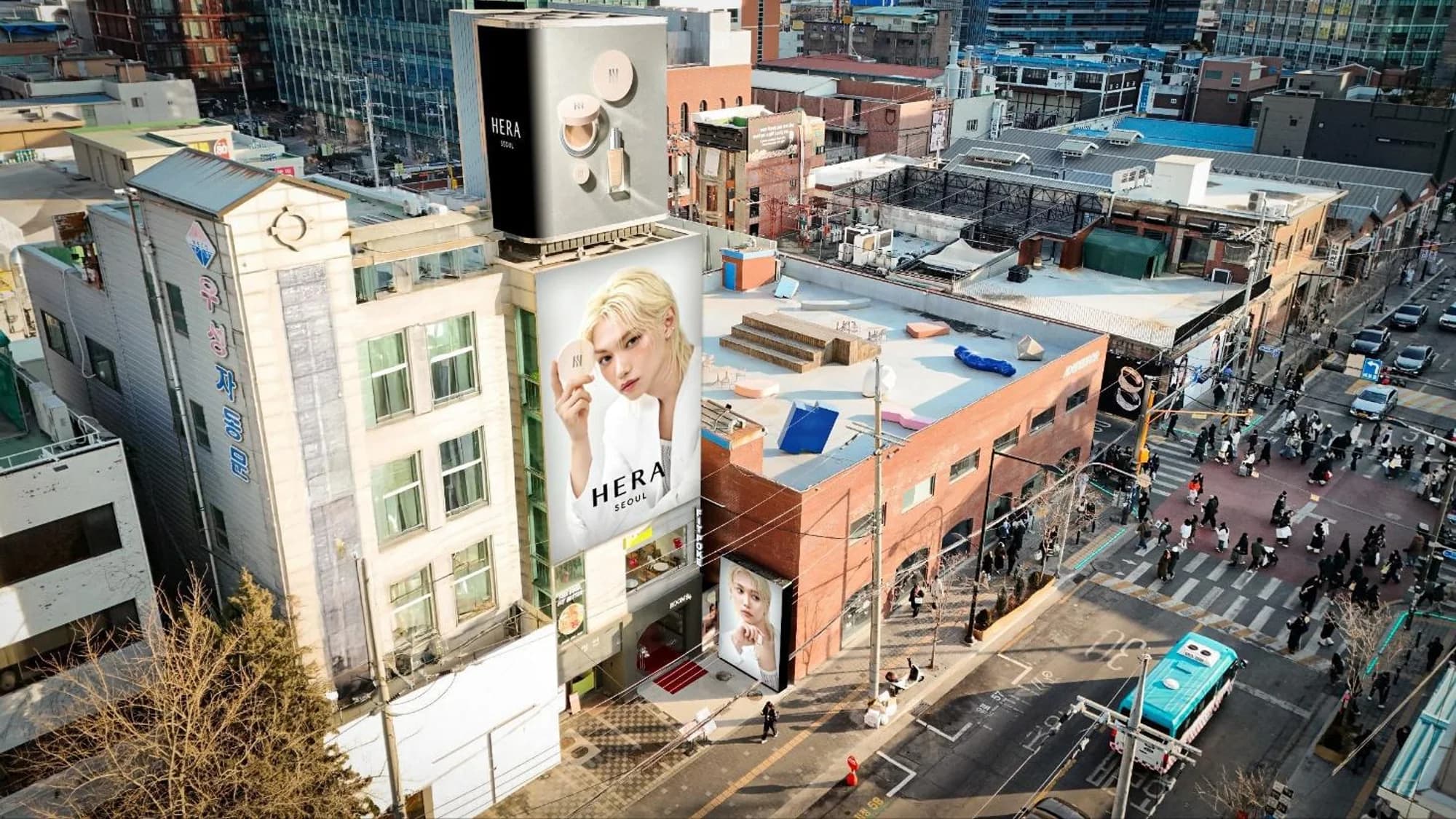 Large format billboard advertising in South Korea: Hera Seoul beauty boards cover a building above a busy city crossing.
