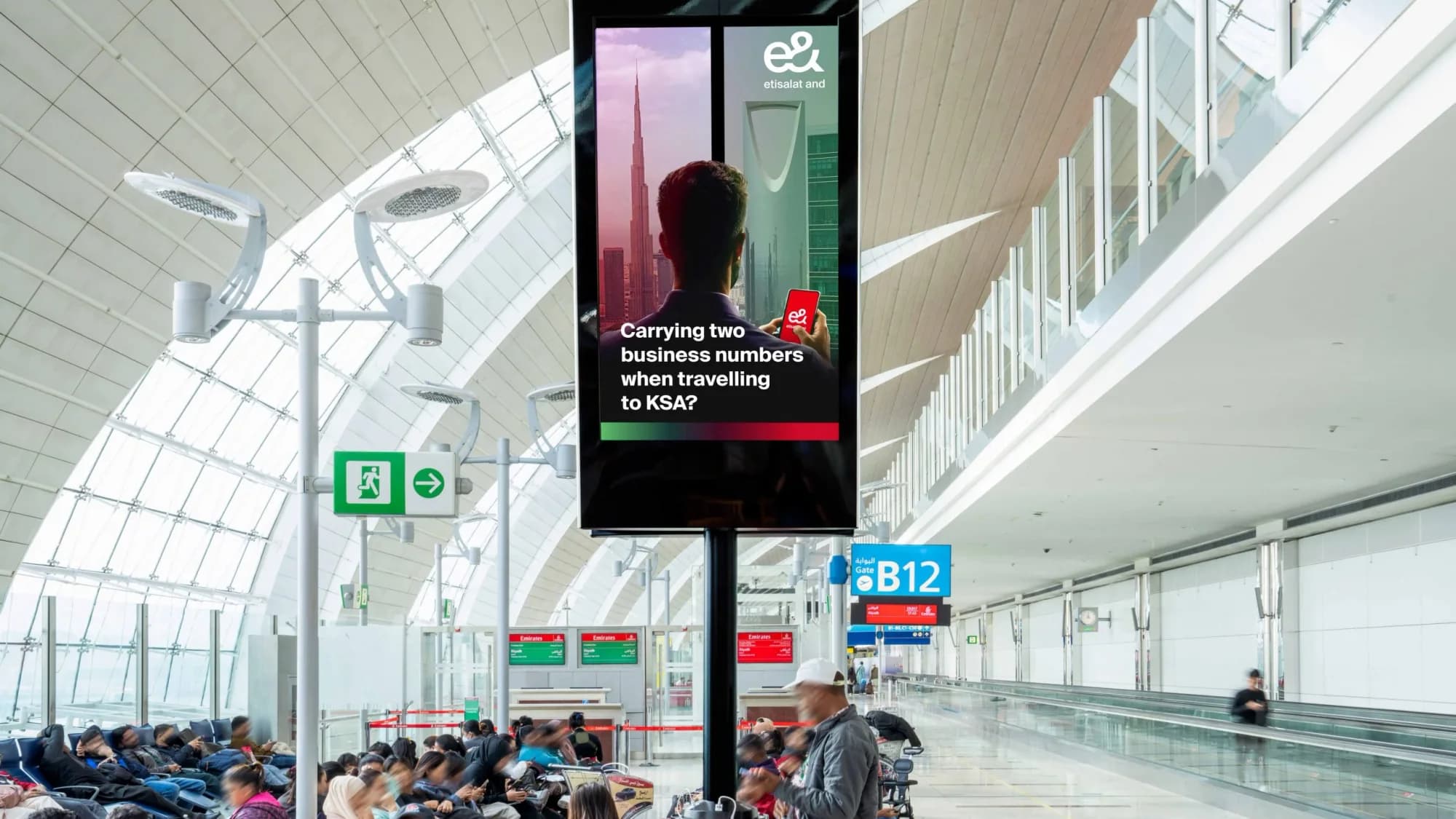 Programmatic airport advertising in the UAE: an e& screen asks about carrying two business numbers when travelling to KSA.