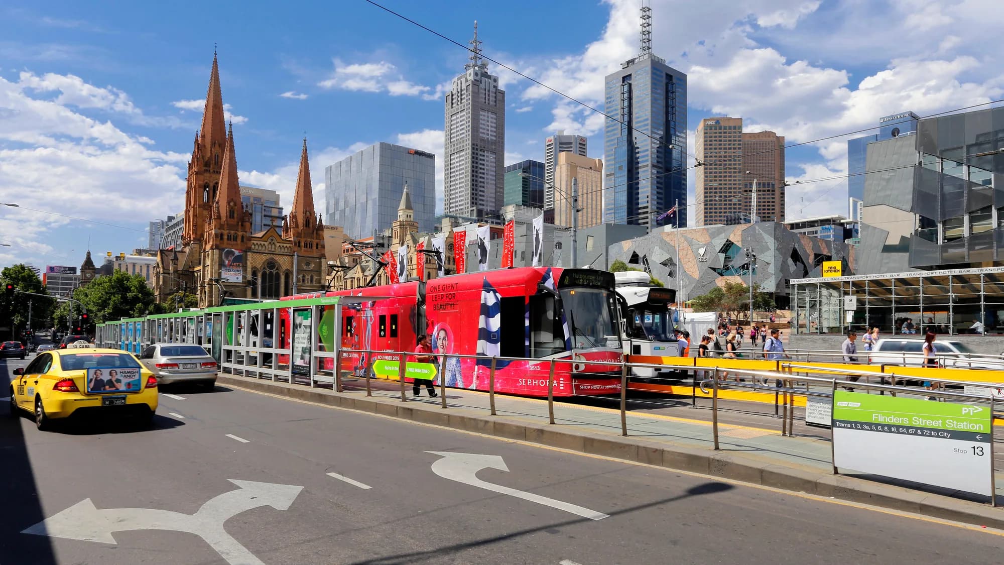 Tram advertising in Melbourne, Australia: an advertising-wrapped tram stops outside Federation Square, with Flinders Street Station and St Paul's Cathedral nearby.