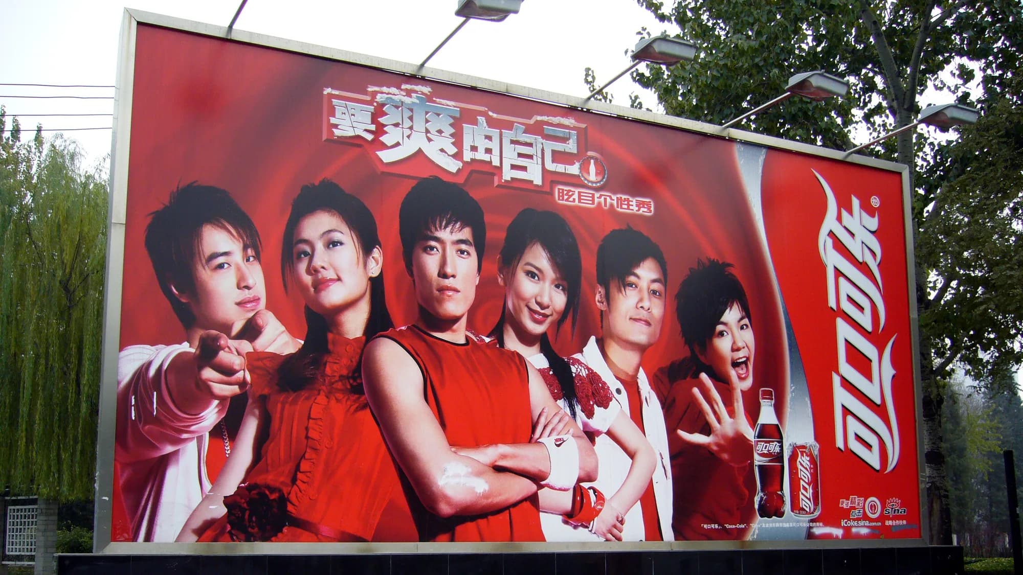 Billboard advertising in Sanlitun, Beijing: a Coca-Cola board shows five people in red beside the Chinese script logo.