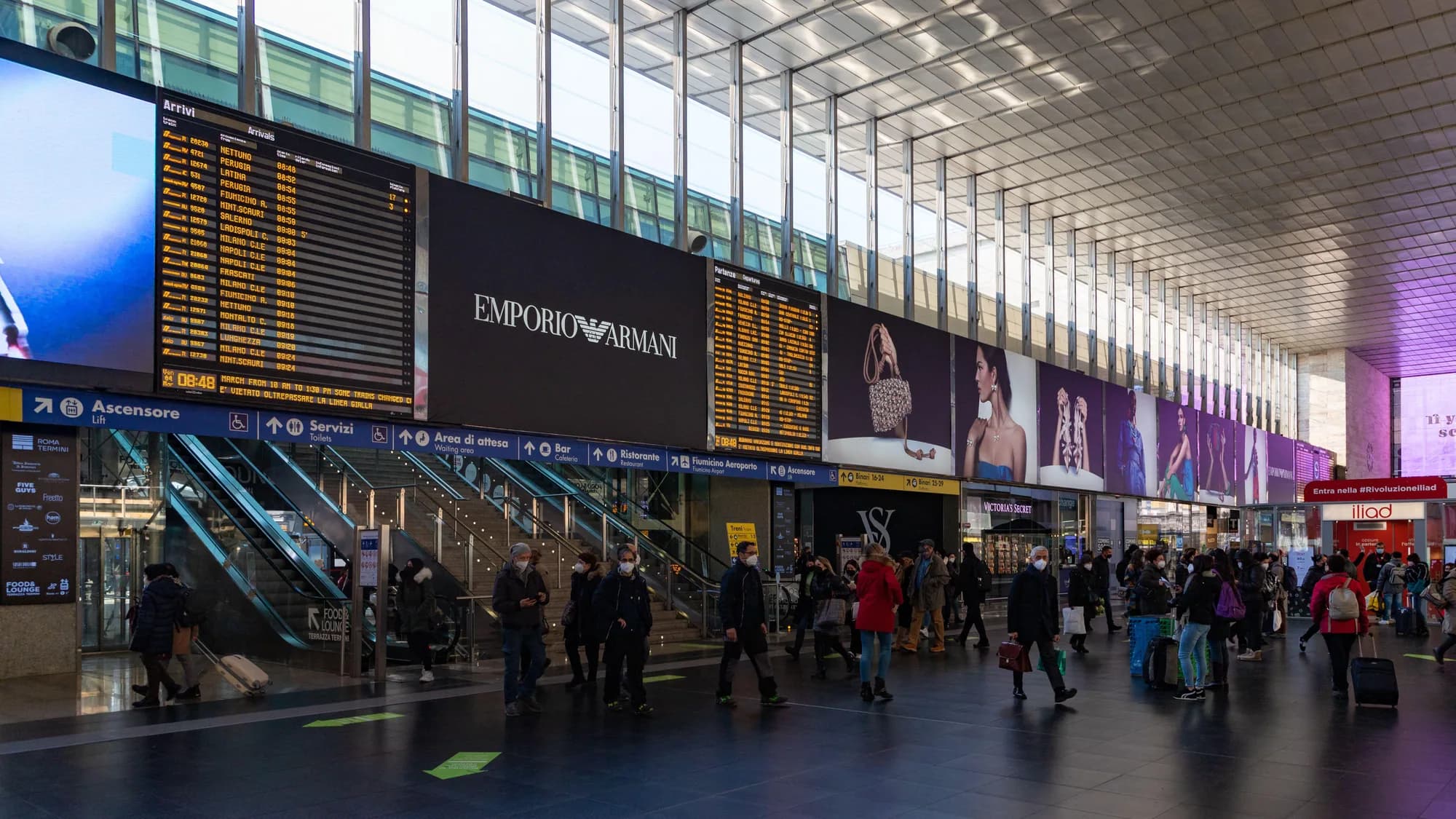 Station advertising at Roma Termini in Rome, Italy: LUISS posters hang under the station name, above signs for the metro and Fiumicino.