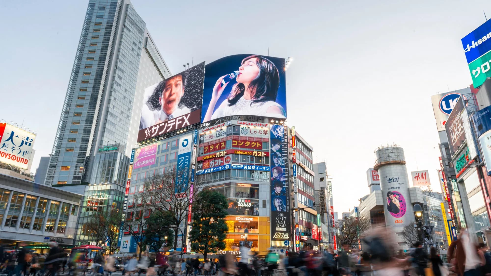 Digital billboard advertising at Shibuya Crossing in Tokyo: Yakult, Rakuten and other giant screens rise over the scramble as crowds gather.