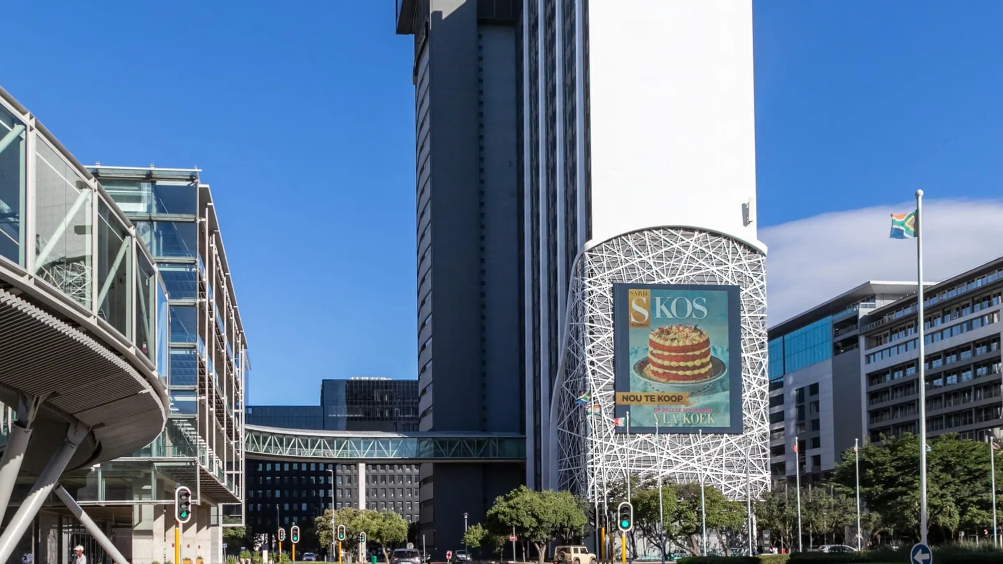 Building banner advertising in the Cape Town CBD, South Africa: the Media24 tower carries a KOS poster of a cake, near a flying South African flag.