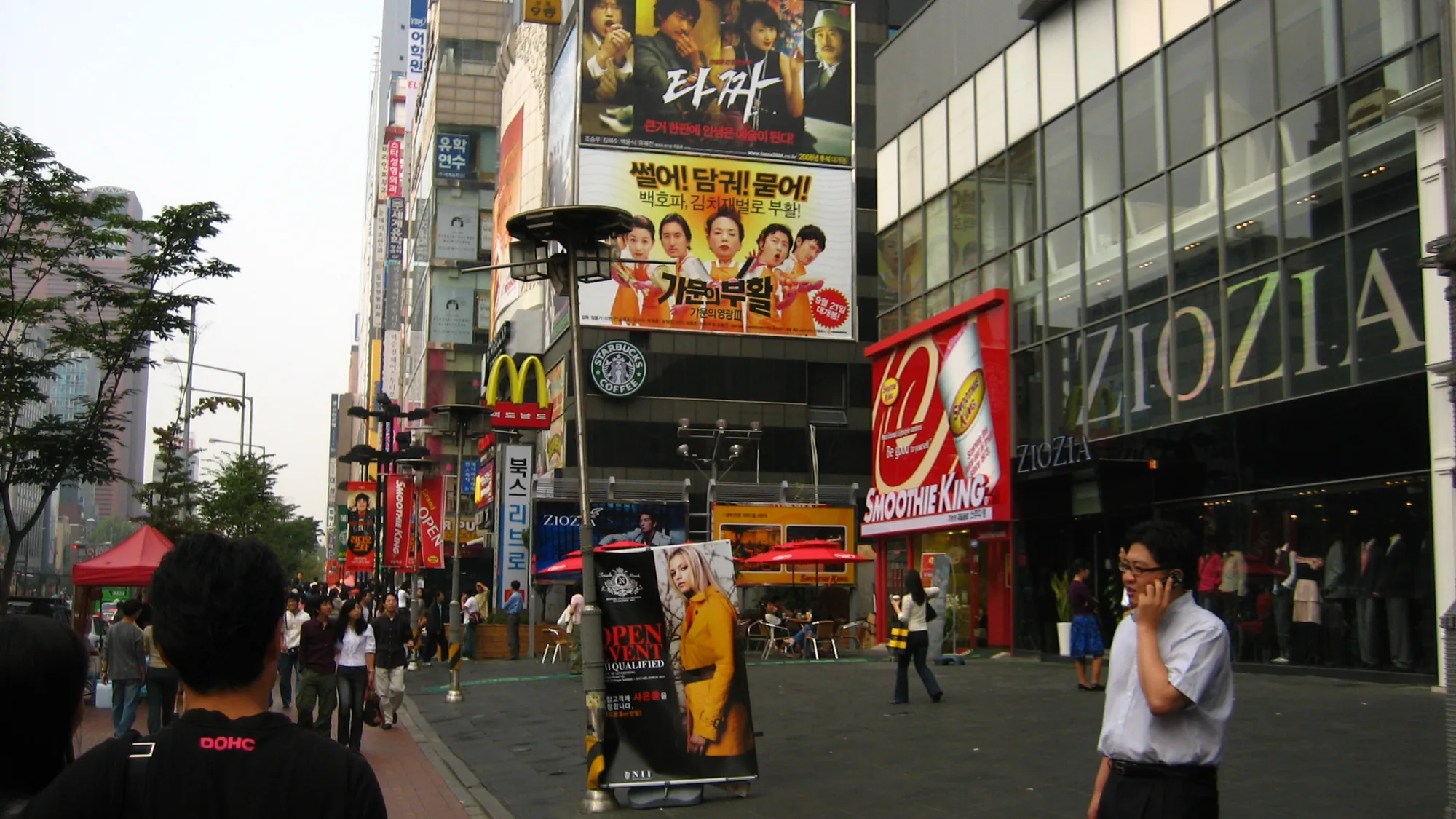 Billboard advertising in Seoul, South Korea: film boards, a Smoothie King and a ZIOZIA store line a busy shopping street.