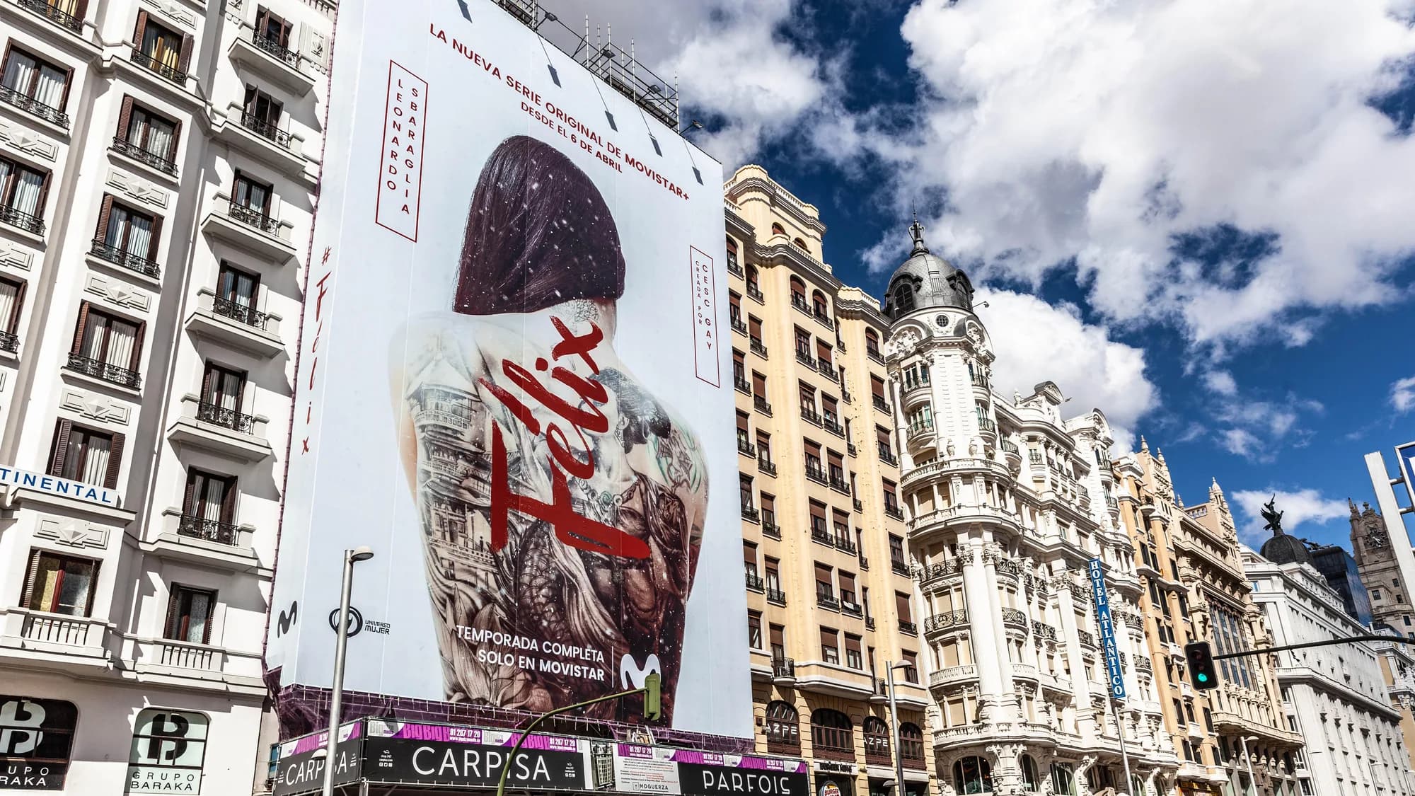 Building banner advertising on Gran Vía in Madrid, Spain: a La Casa de Papel wrap sits beside a poster reading lo ponemos así, grandecito.