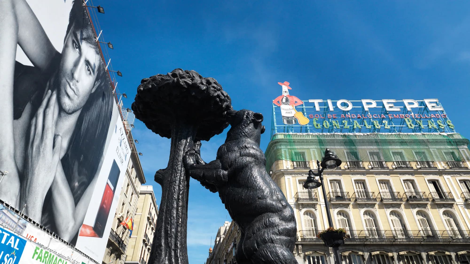 Outdoor advertising in Madrid, Spain: the Tio Pepe rooftop sign stands behind the bear and strawberry tree statue, next to a large fashion billboard.