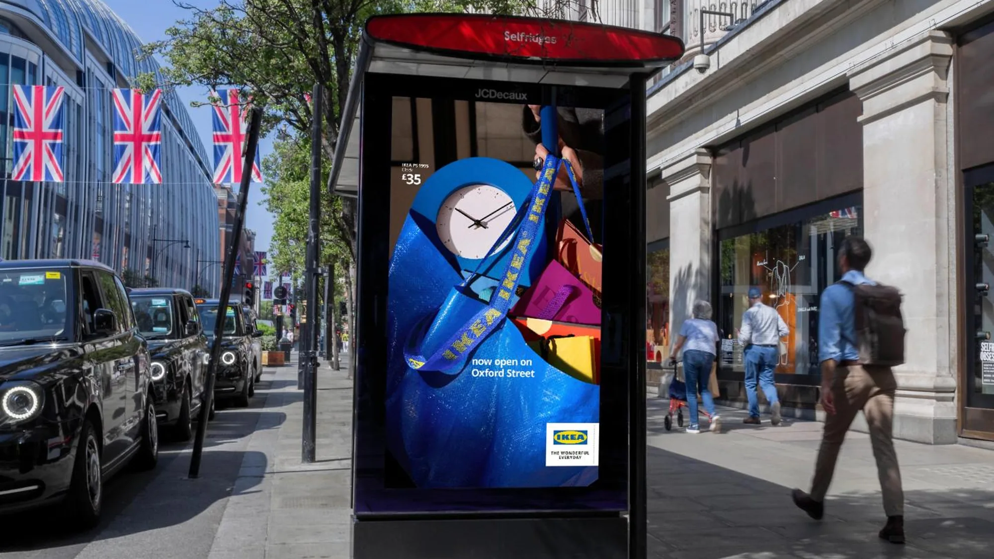 Street furniture advertising on Oxford Street in London, in the United Kingdom: a bus shelter screen for IKEA reads now open on Oxford Street, beside black cabs and Union Jack flags.