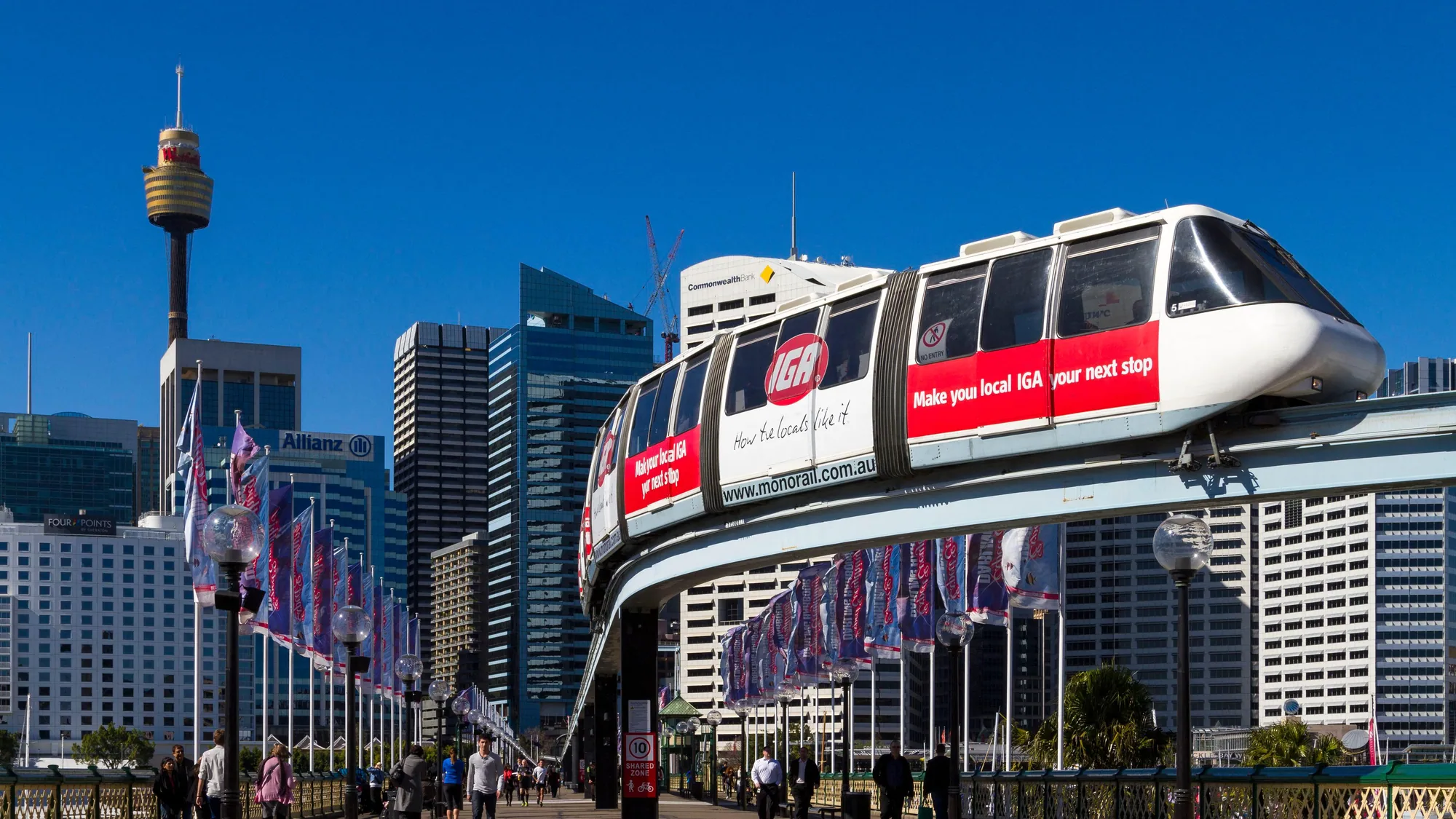 Transit advertising in Sydney, Australia: a monorail wrapped for IGA passes Sydney Tower, with the line Make your local IGA your next stop.