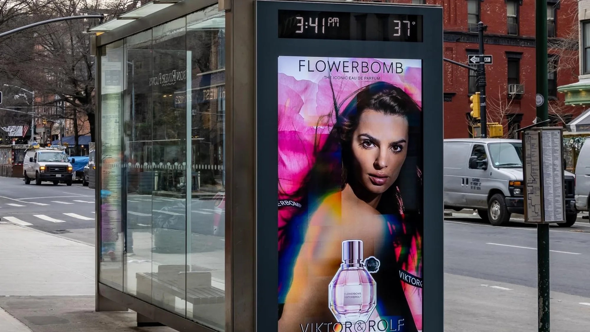 Programmatic street furniture advertising in New York: a bus shelter screen advertises Viktor & Rolf Flowerbomb beside a city street, showing 3:41pm and 37 degrees.