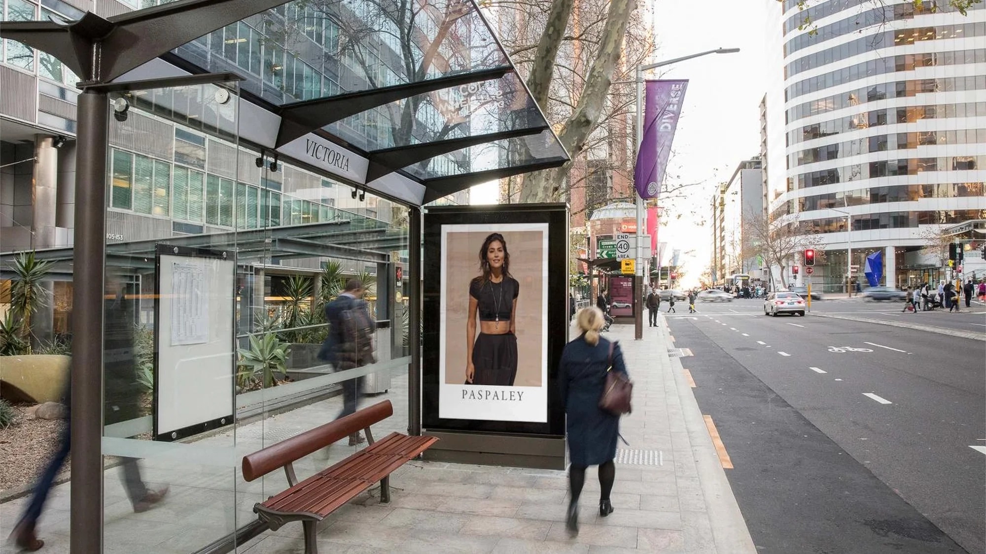 Street furniture advertising in Victoria, Australia: a shelter with Victoria on the roof shows a Paspaley advertisement of a woman in black.