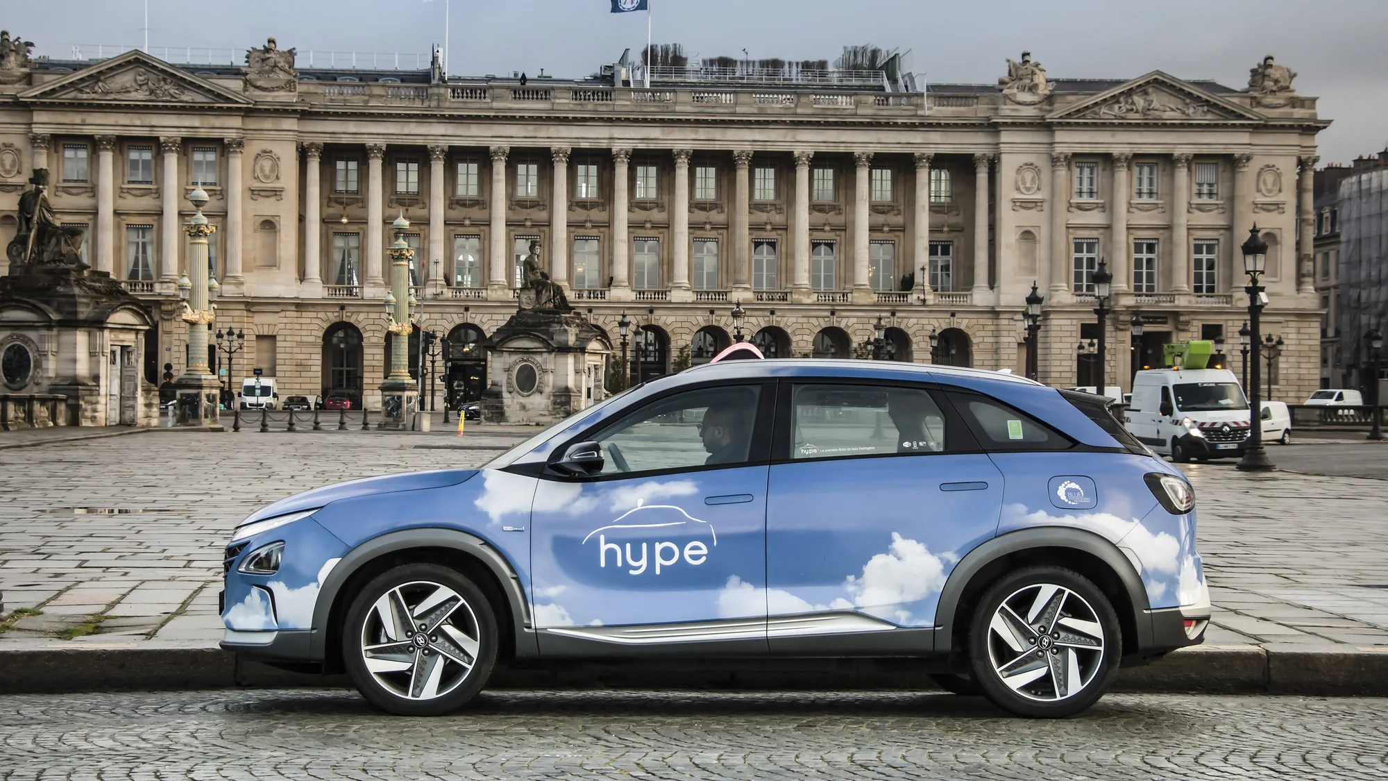 Taxi advertising in Paris, in France: a Hype taxi in a cloud livery waits in a square in front of a colonnaded building.
