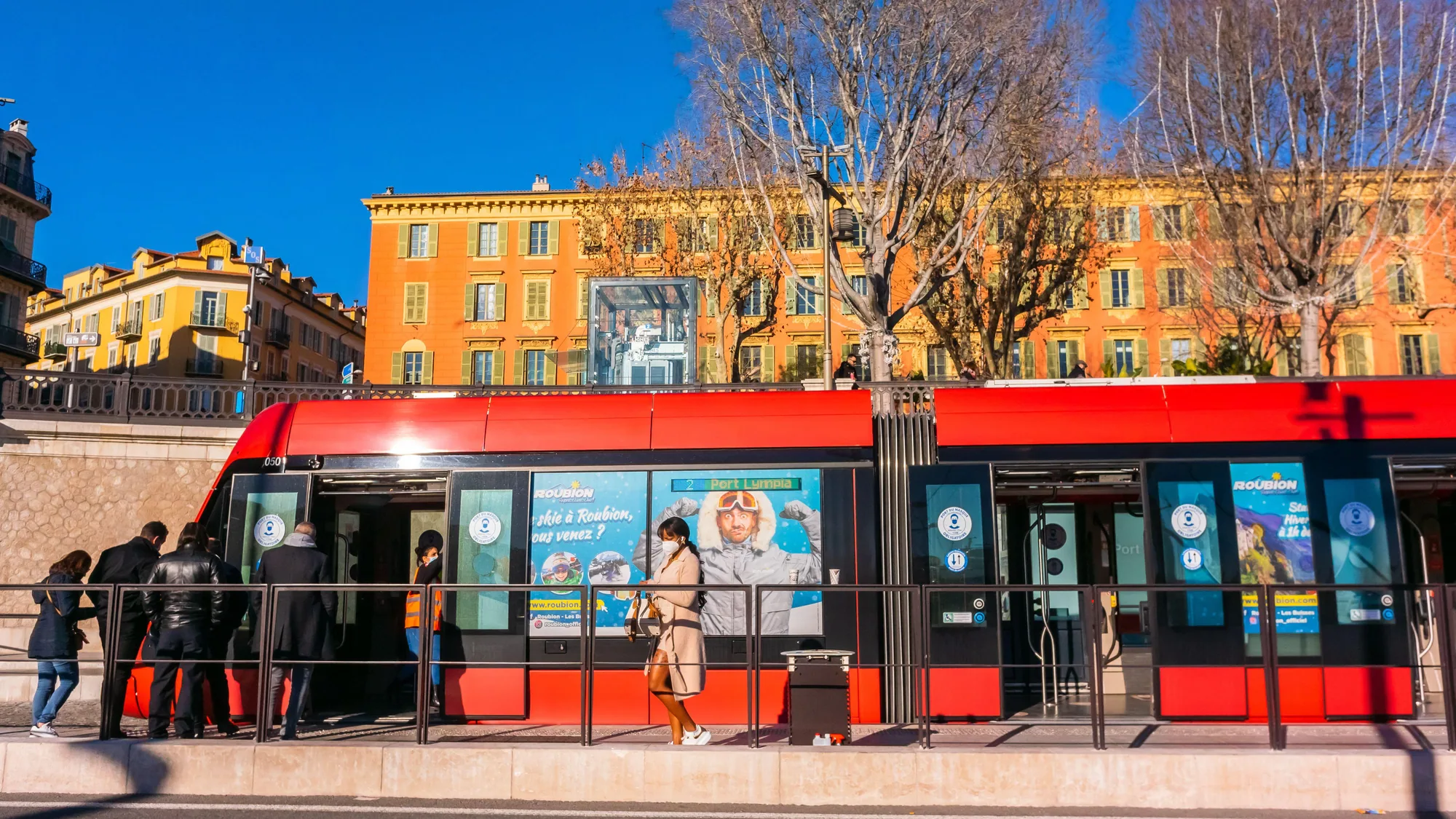 Tram advertising in the south of France: a red tram carries window posters for skiing in Roubion.
