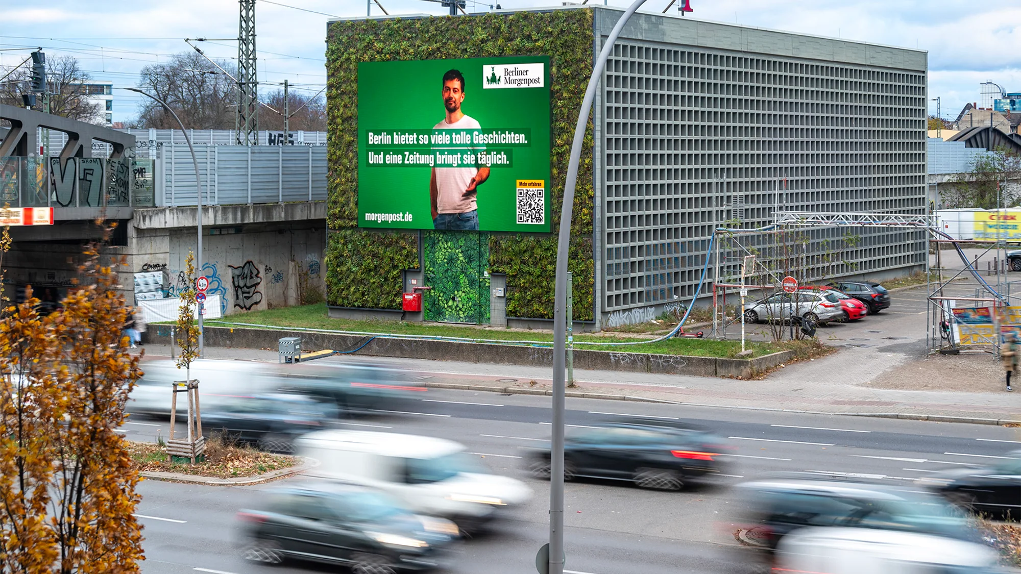 Building banner advertising in Berlin, Germany: a Berliner Morgenpost board on a planted wall reads Berlin bietet so viele tolle Geschichten.