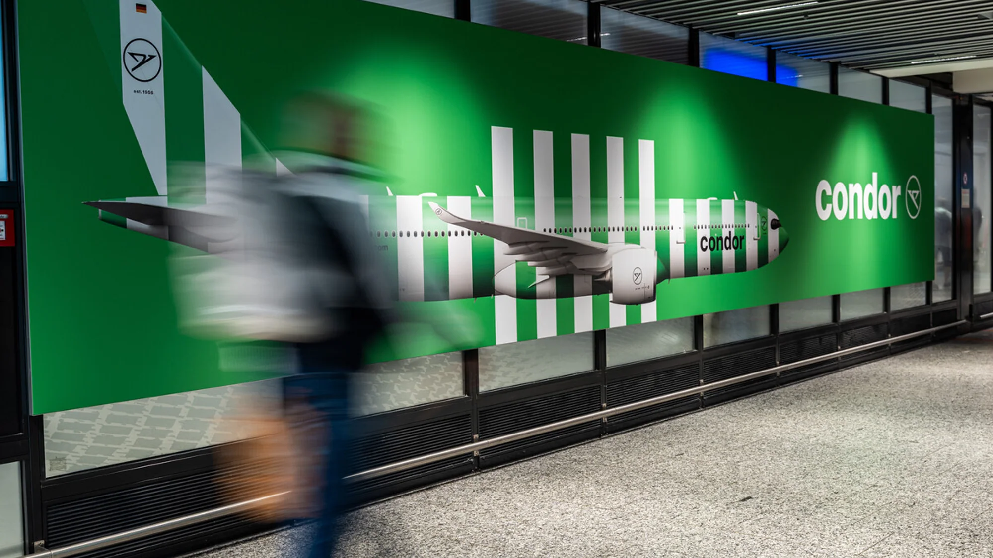 Large format banner advertising for Condor in Germany: a green wall shows a green and white striped jet.
