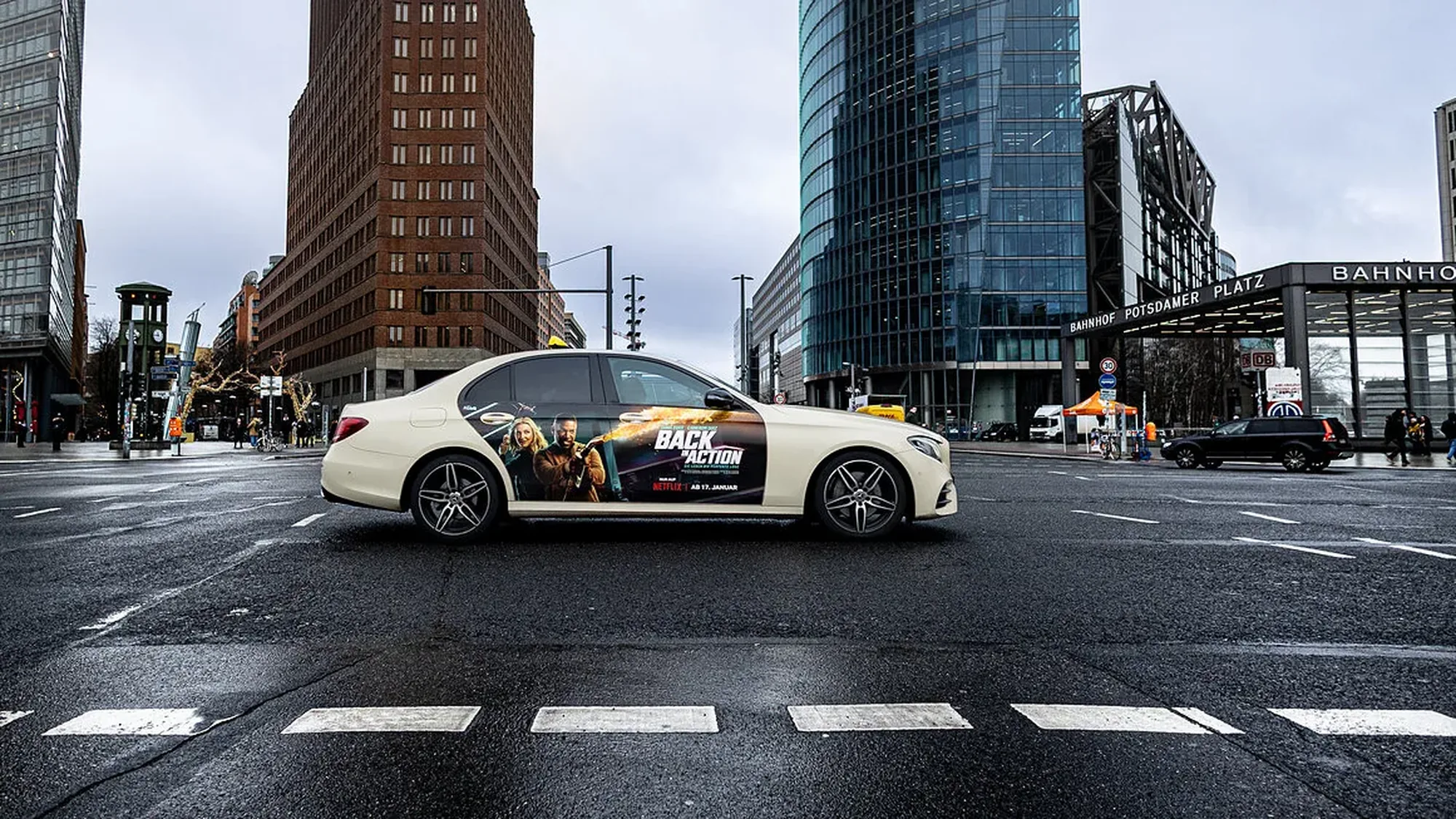 Taxi advertising at Potsdamer Platz in Berlin, Germany: a cream Mercedes carries a Back in Action wrap on the rear door.