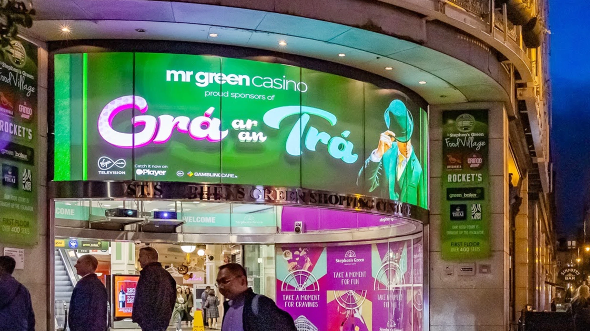 Digital out-of-home advertising in Dublin, Ireland: a curved screen at St Stephen's Green Shopping Centre promotes Mr Green Casino as proud sponsors of Grá ar an Trá.