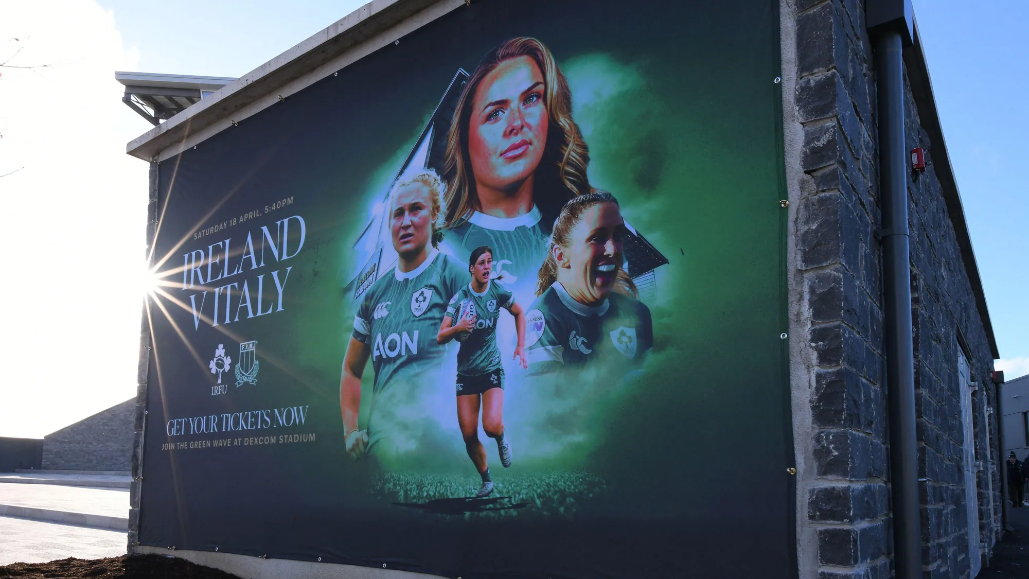 Large format banner advertising in Ireland: a board for an Ireland versus Italy women's rugby match tells fans to get tickets and join the green wave at Dexcom Stadium.