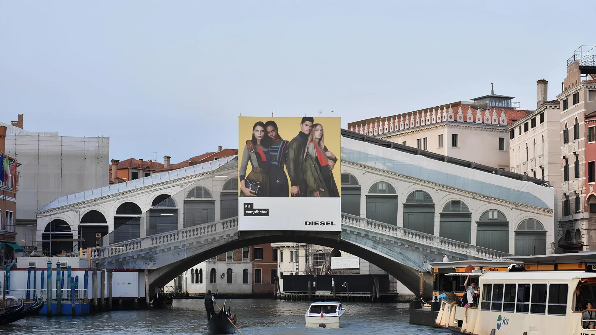 Bridge banner advertising in Venice, Italy: a Diesel billboard reading it's complicated stands on the Rialto Bridge above the canal.
