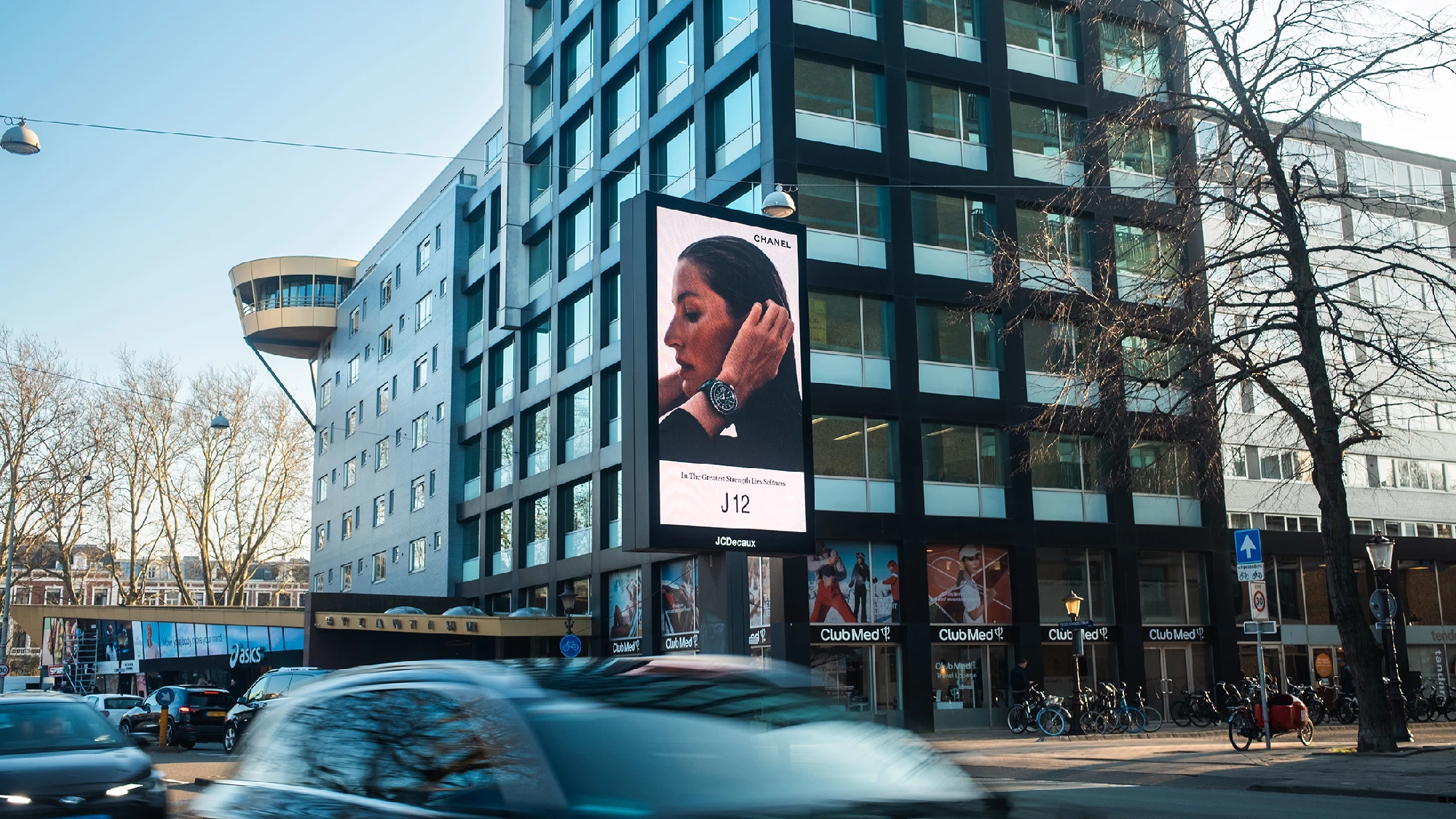 A portrait billboard on a Dutch street in the Netherlands shows Chanel's J12 advertising campaign, with a woman in profile and the watch name J12.