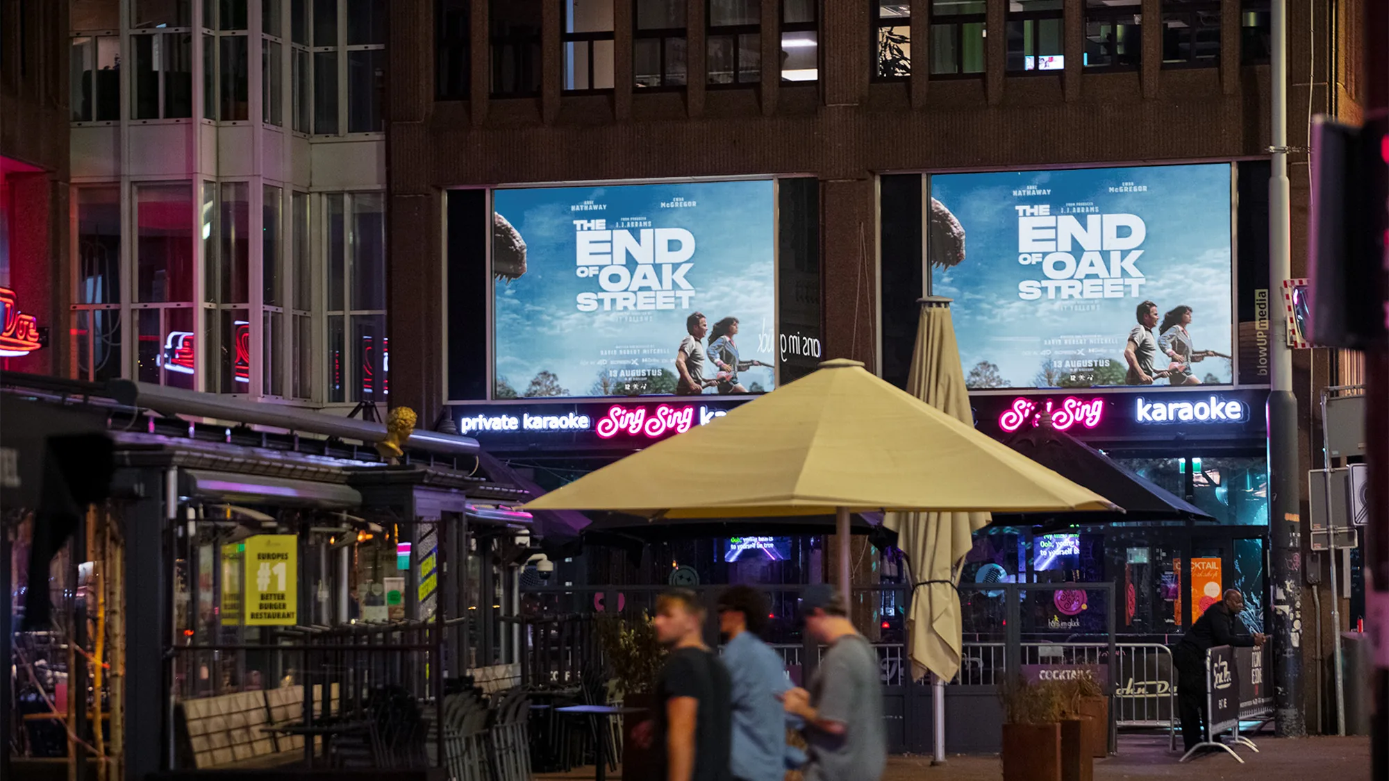 Building banner advertising in the Netherlands: two screens show Warner Bros. posters for the film The End of Oak Street above a karaoke front.