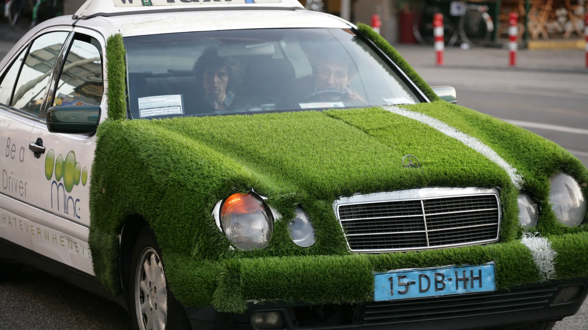 Taxi advertising in the Netherlands: a Mercedes taxi is covered in grass, with a door reading Be a Driver beside a Mint logo.
