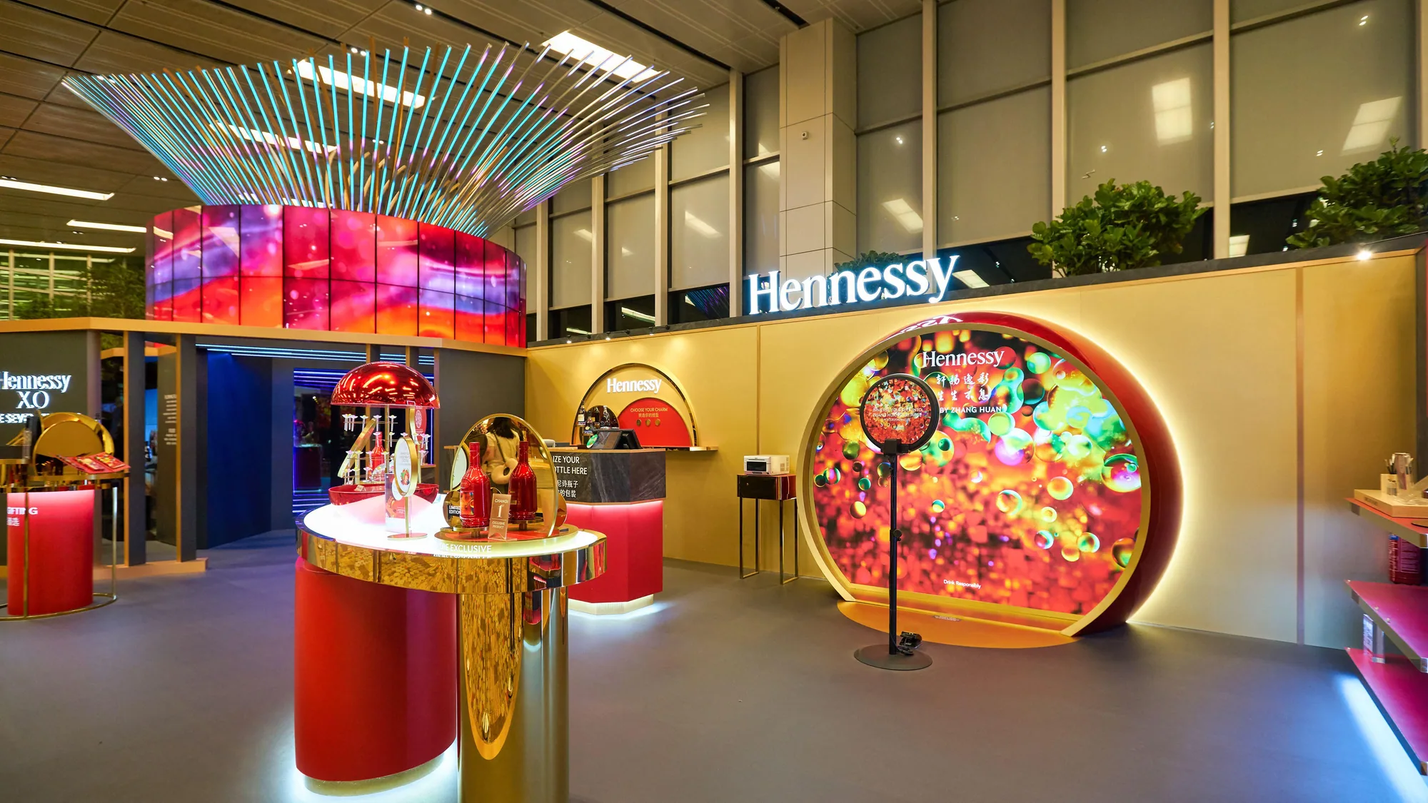A Hennessy brand activation at Singapore Changi Airport: a circular illuminated display, red and gold counters and bottles set out for tasting.