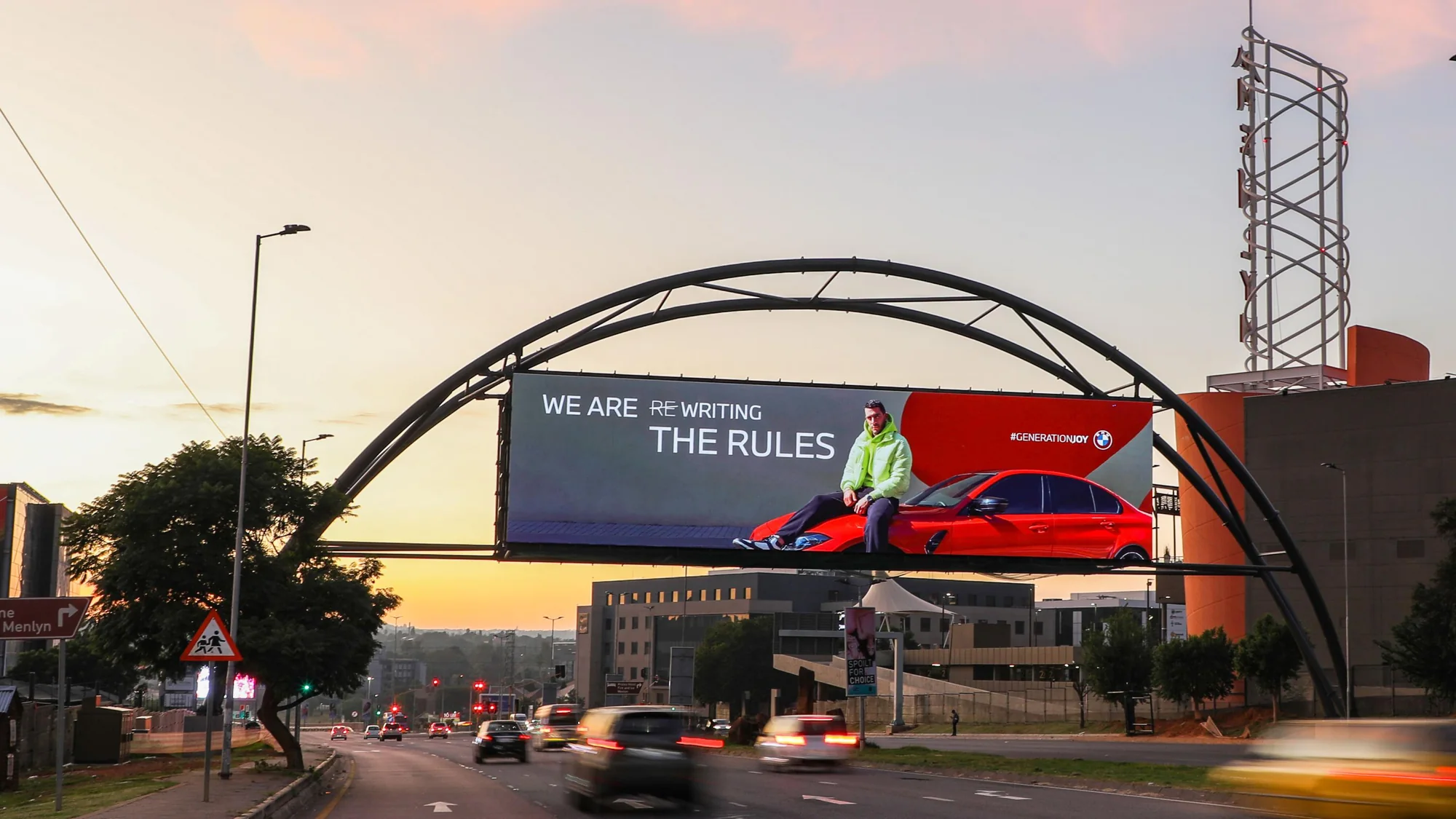 Billboard advertising in Pretoria, South Africa: an arched board shows a BMW campaign, We are rewriting the rules, near a sign for Menlyn.