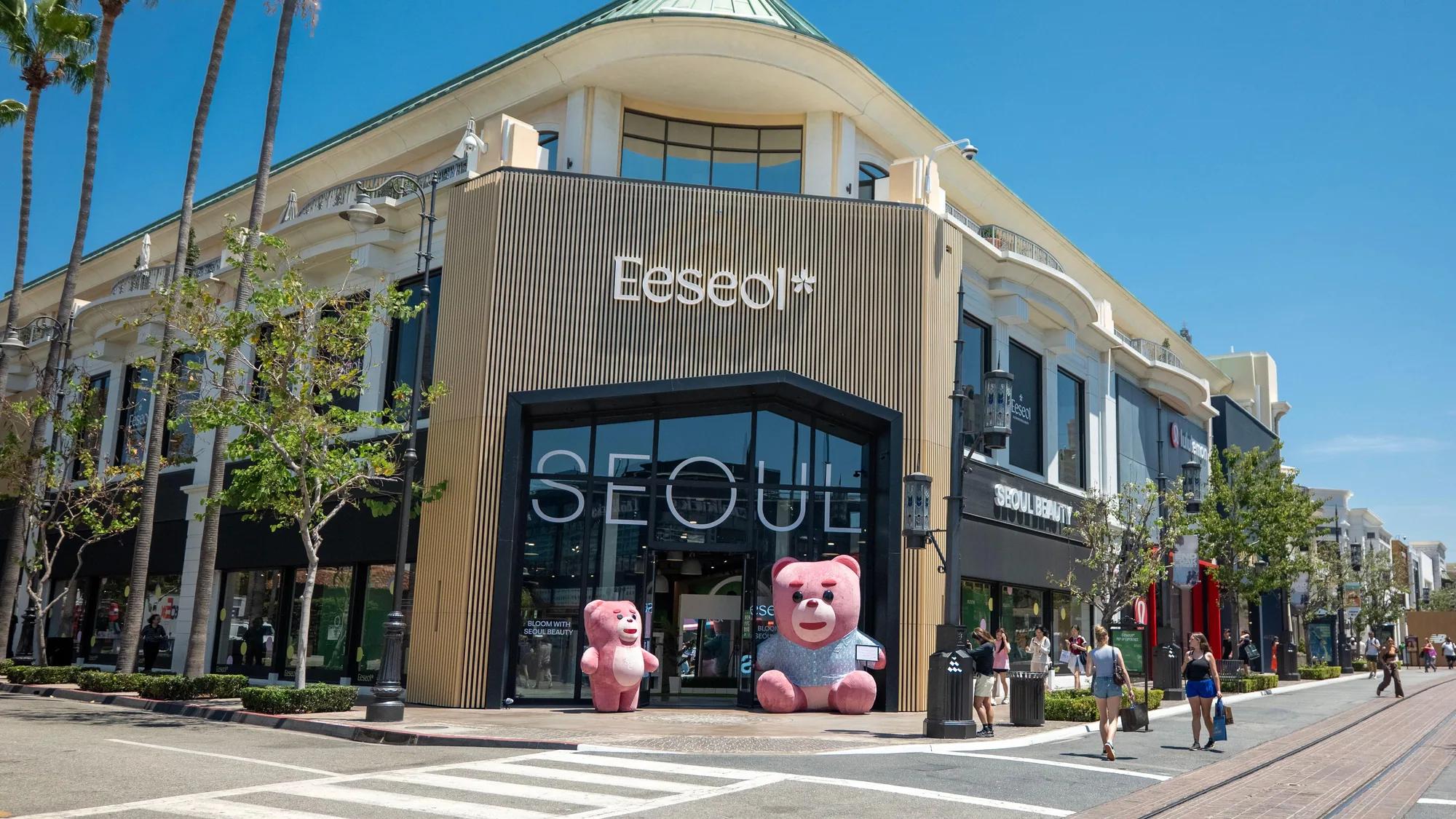 A brand activation from Seoul: pink teddy bears stand outside an Eeseol pop-up at The Grove in Los Angeles, beside palm trees and tram tracks.