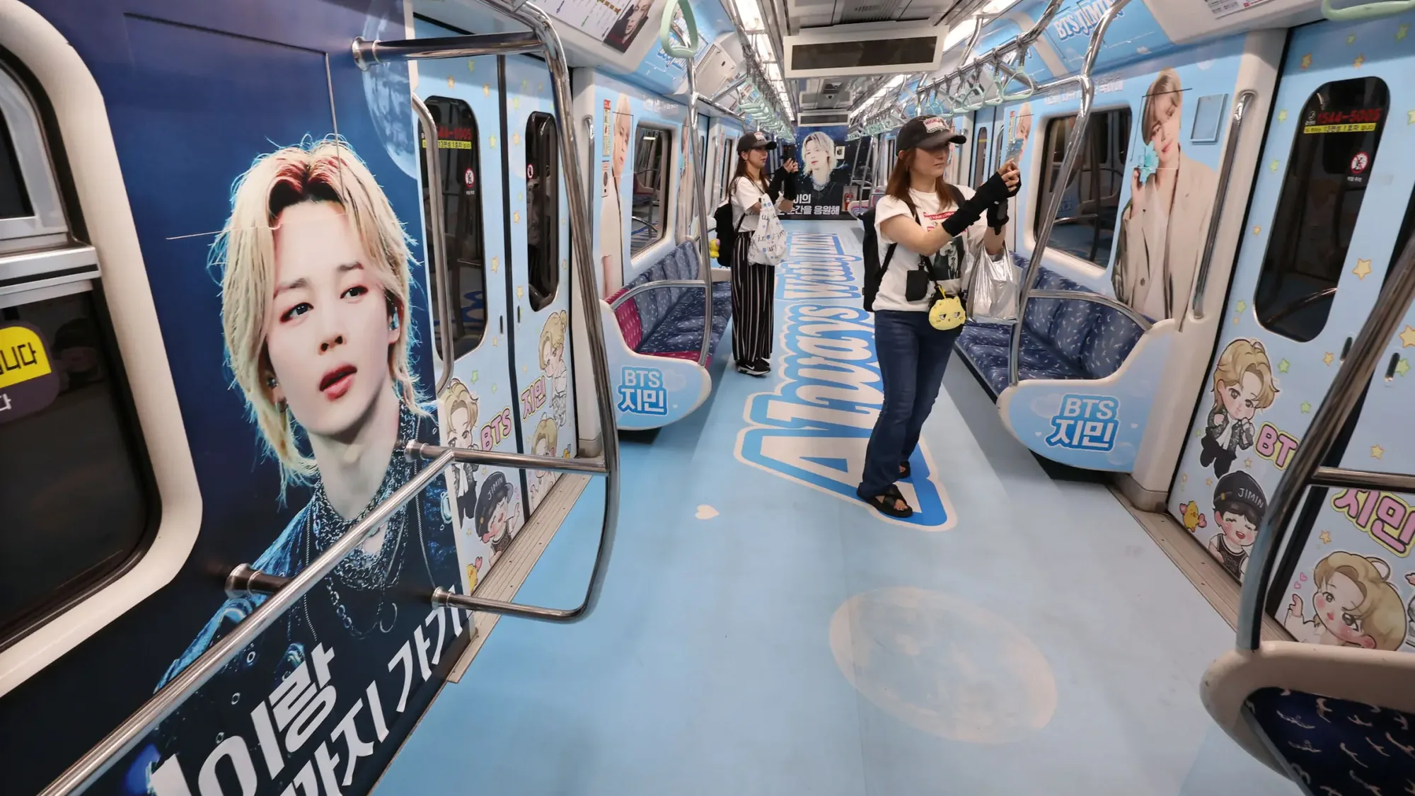 Metro advertising in South Korea: a carriage is wrapped with BTS and Jimin portraits, cartoons and pale blue flooring.