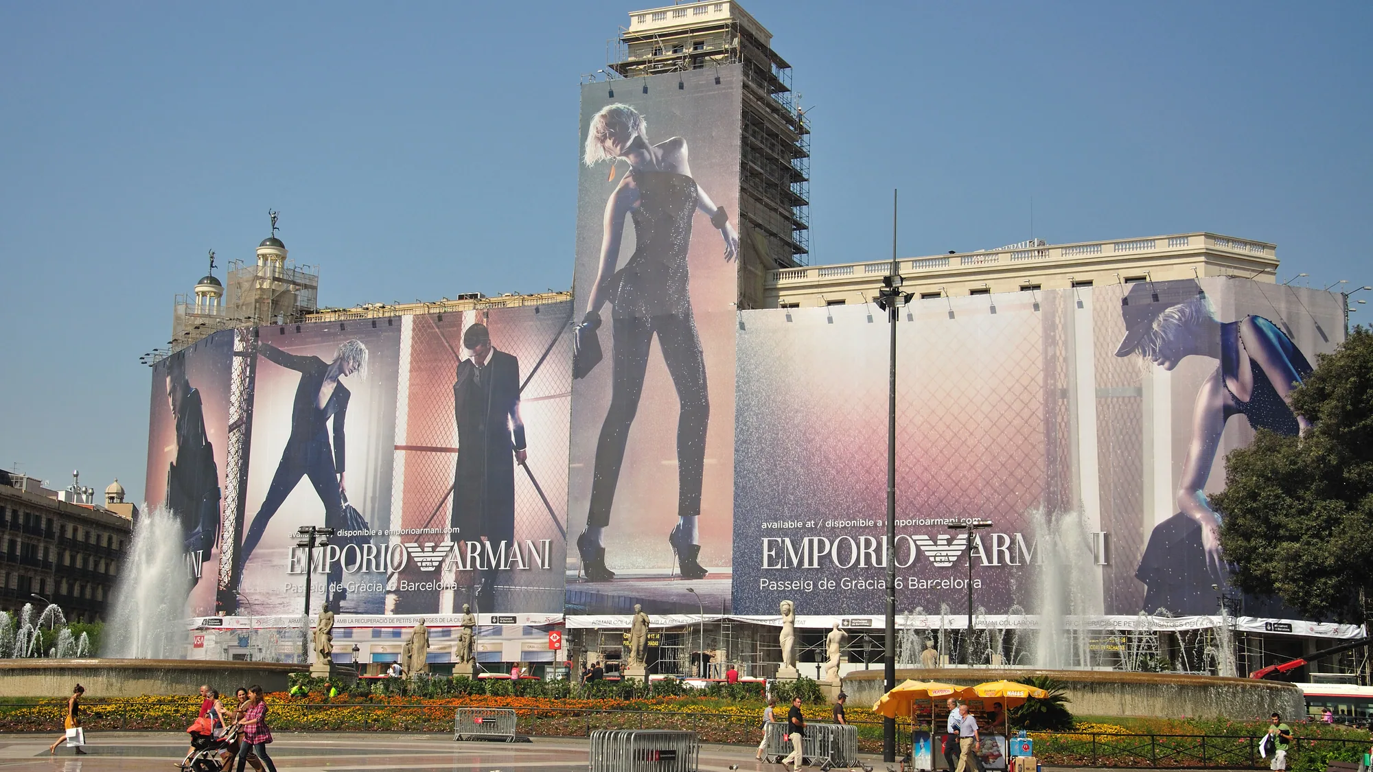 Building banner advertising at Plaça de Catalunya in Barcelona, Spain: Emporio Armani banners cover scaffolding beside the fountain.