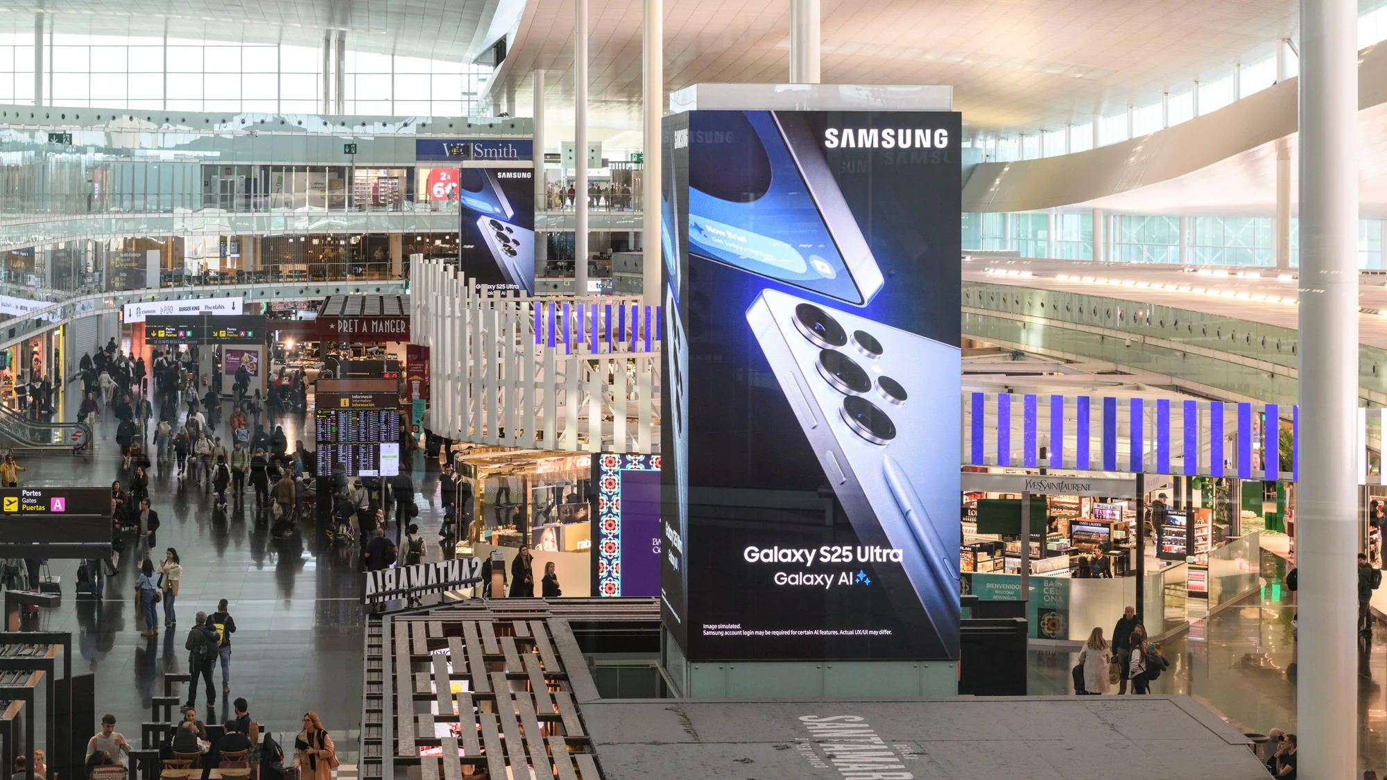 Digital out-of-home advertising in a Spanish airport: a tall Samsung Galaxy S25 Ultra screen stands in a busy terminal.
