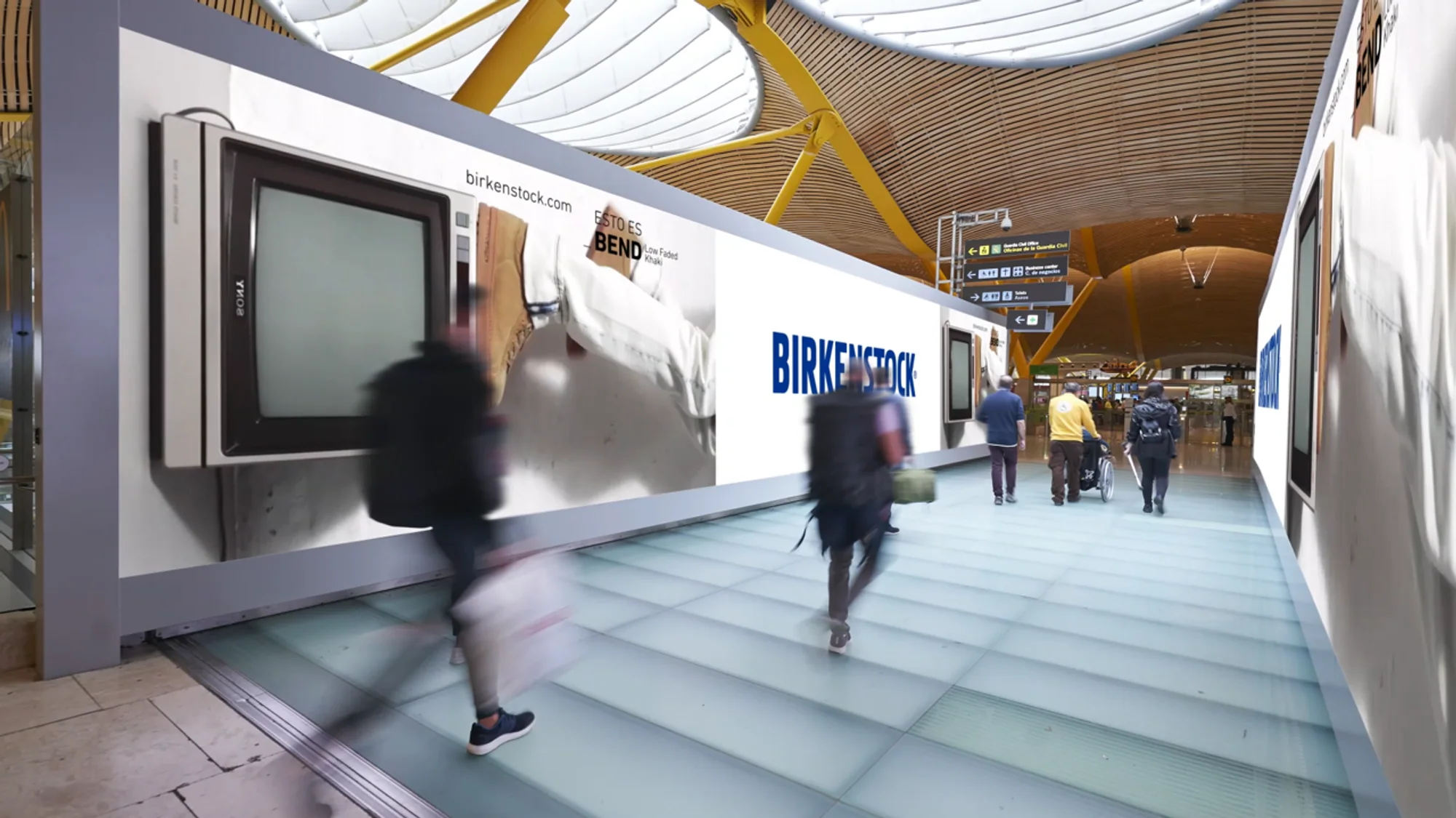 Large format banner advertising at Madrid airport in Spain: a long Birkenstock banner reading Esto es Bend lines a moving walkway.