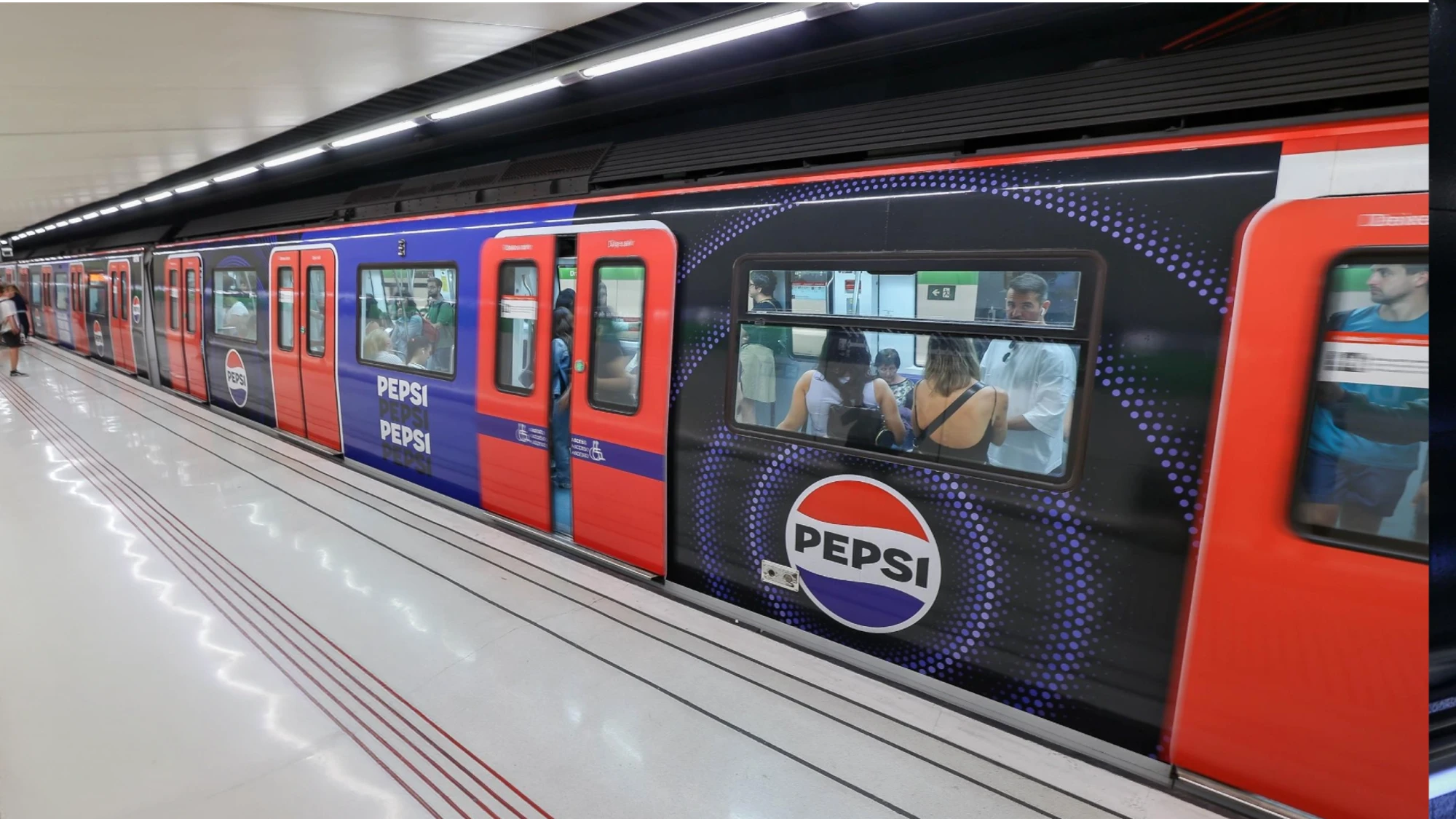 Metro advertising in Spain: a red and blue Pepsi-wrapped train waits at an underground platform.