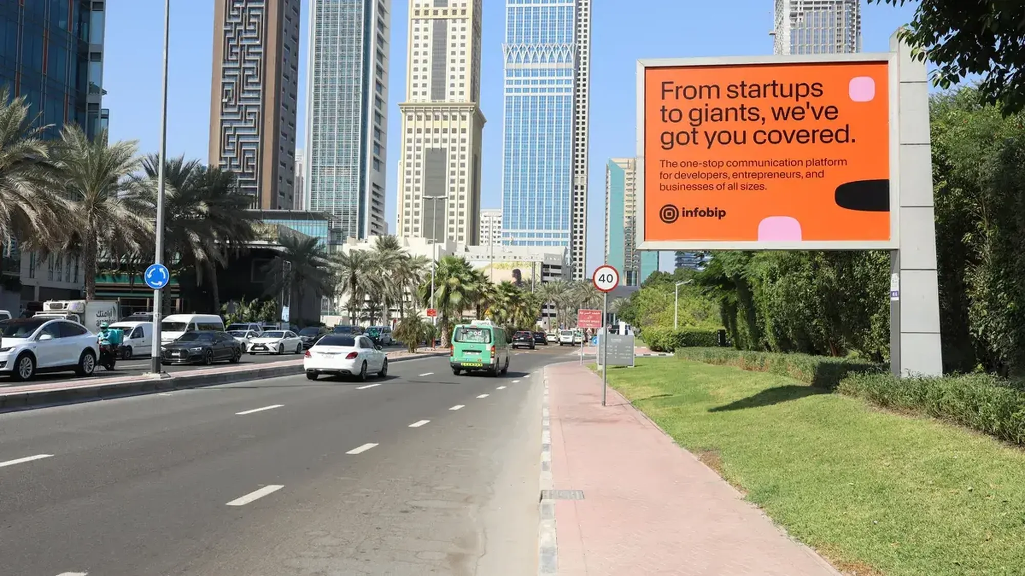 Billboard advertising in the UAE: an orange roadside board for Infobip reads From startups to giants, we've got you covered, beside palms and tower blocks.