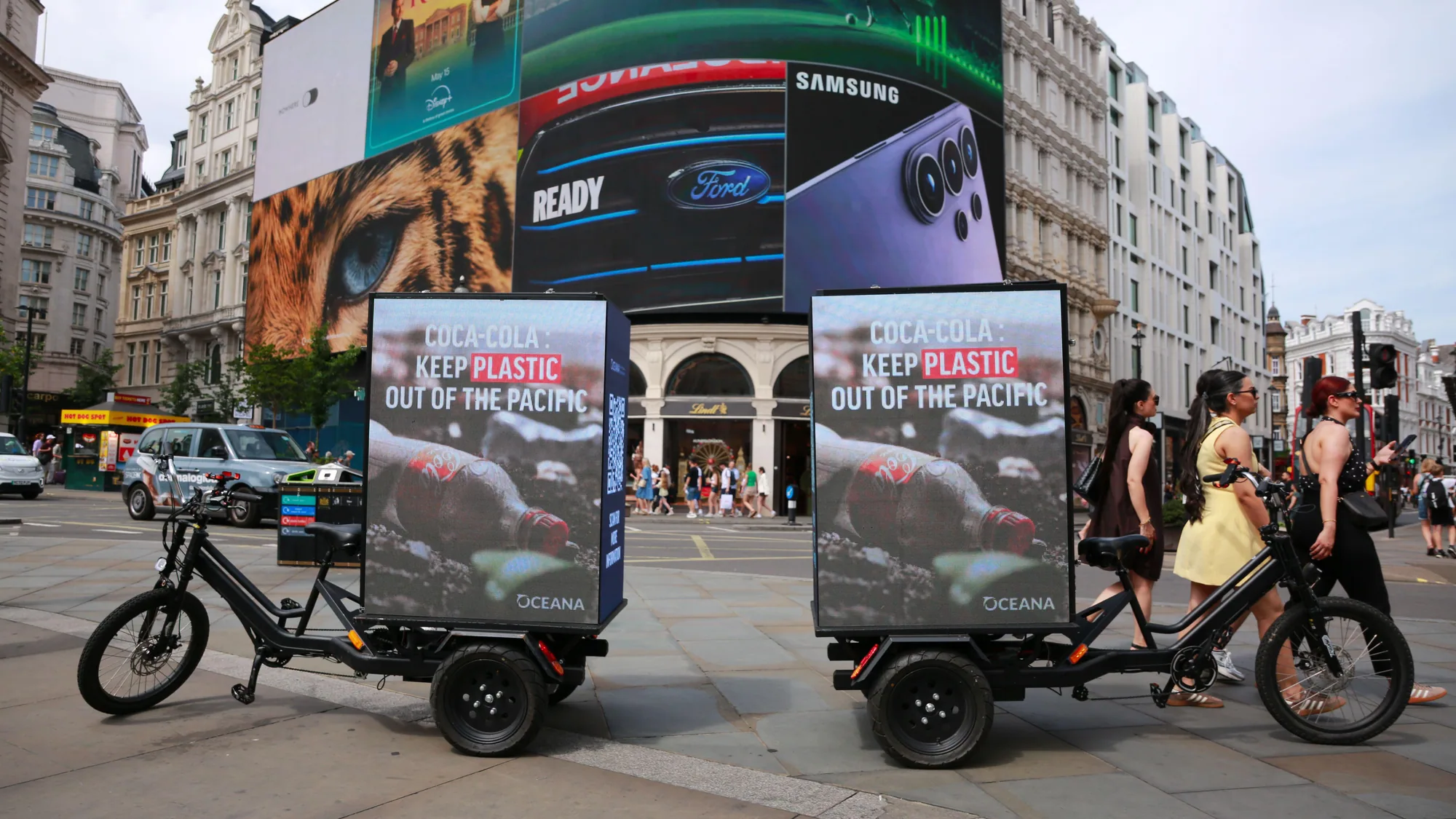A brand activation in Piccadilly Circus, London, in the United Kingdom: Oceana cargo bikes read Keep plastic out of the Pacific, with Coca-Cola branding.
