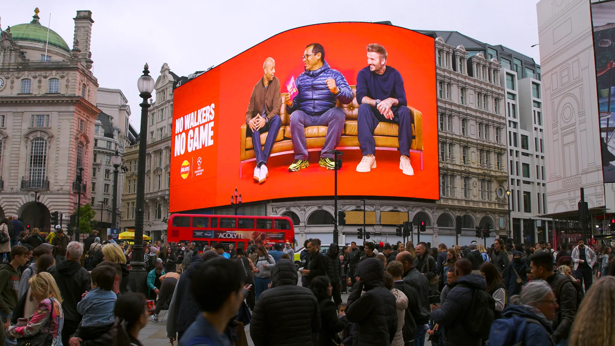 Billboard advertising at Piccadilly Lights in London, in the United Kingdom: a Walkers screen reads No Walkers, no game, with three men on a sofa.