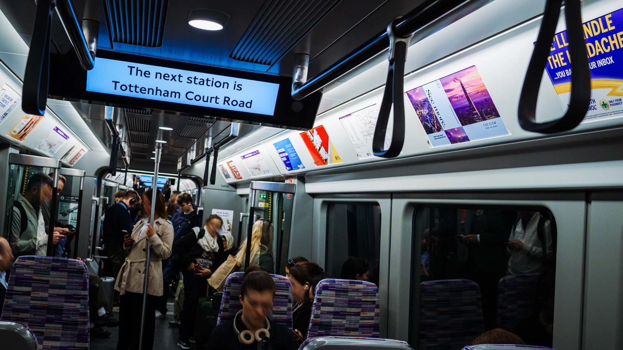 London Underground advertising in the United Kingdom: carriage cards line a train as the display reads Tottenham Court Road.
