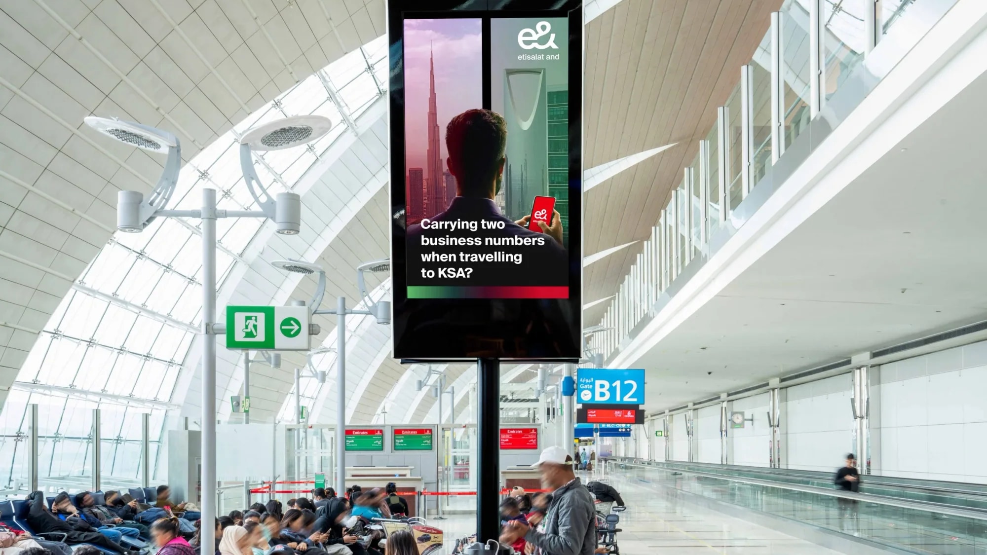 Programmatic airport advertising in the UAE: an e& screen asks about carrying two business numbers when travelling to KSA.