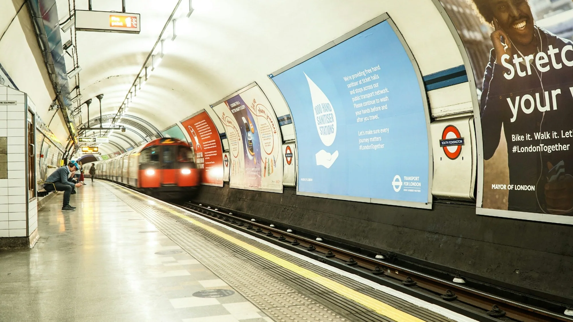 London Underground advertising in the United Kingdom: a Tube train arrives at South Kensington beside Transport for London posters.
