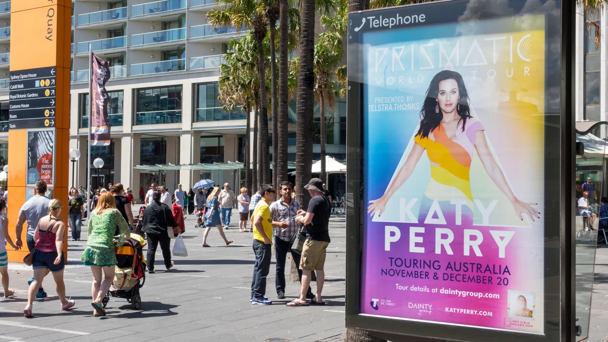 Outdoor advertising at Circular Quay in Sydney, Australia: a Lipton Ice Tea Sparkling poster stands on the promenade beside wayfinding for the Sydney Opera House.