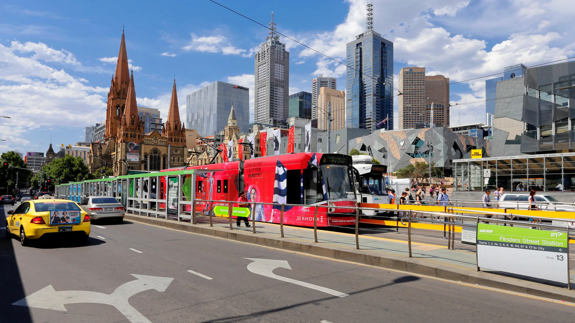 Tram advertising in Melbourne, Australia: an advertising-wrapped tram stops outside Federation Square, with Flinders Street Station and St Paul's Cathedral nearby.