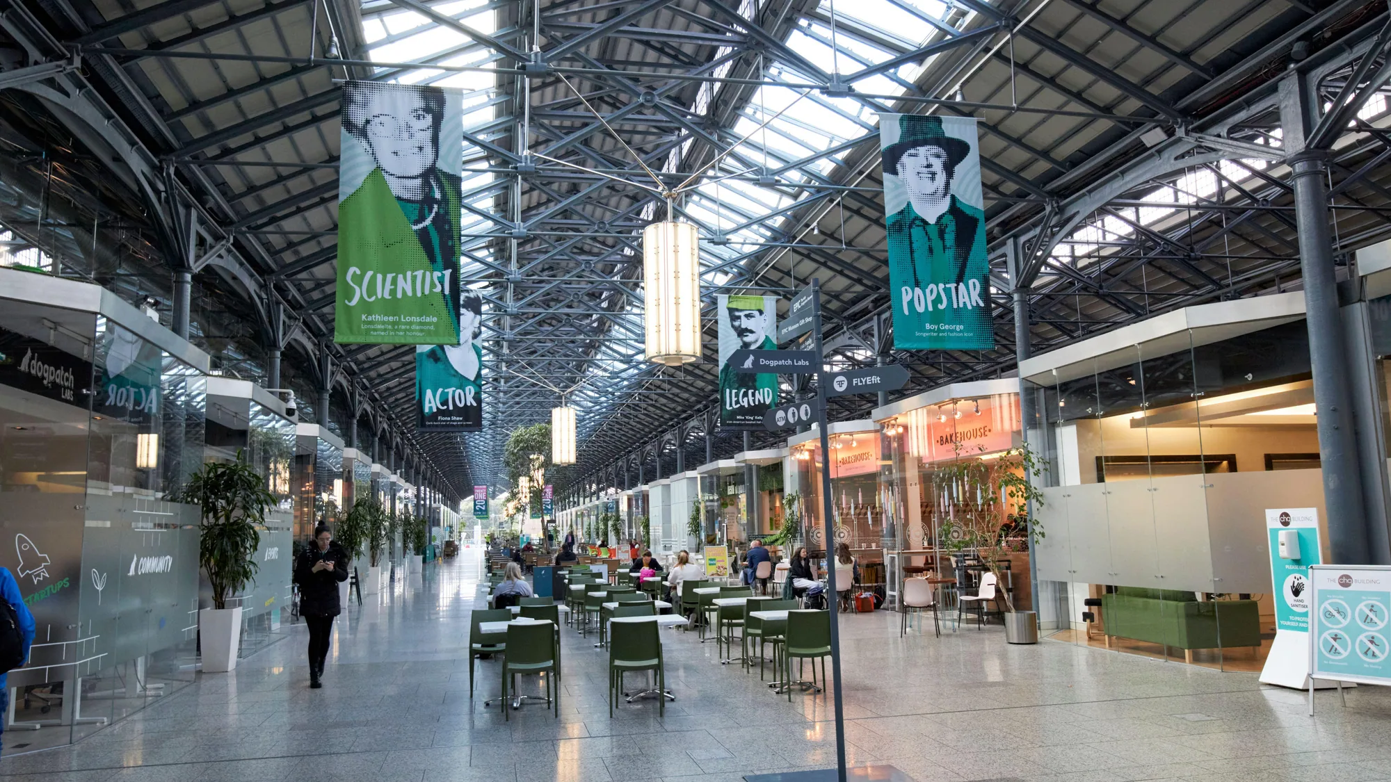Indoor advertising in the Dublin Docklands, Ireland: portrait banners labelled scientist, actor and popstar hang in a glazed hall of cafes and shops.