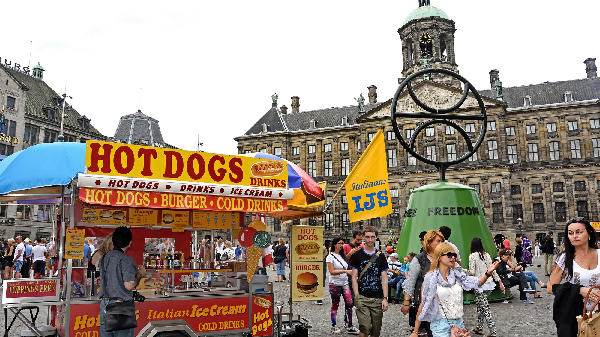Dam Square in Amsterdam, the Netherlands: Madame Tussauds lettering and two hanging figures mark a stone building.
