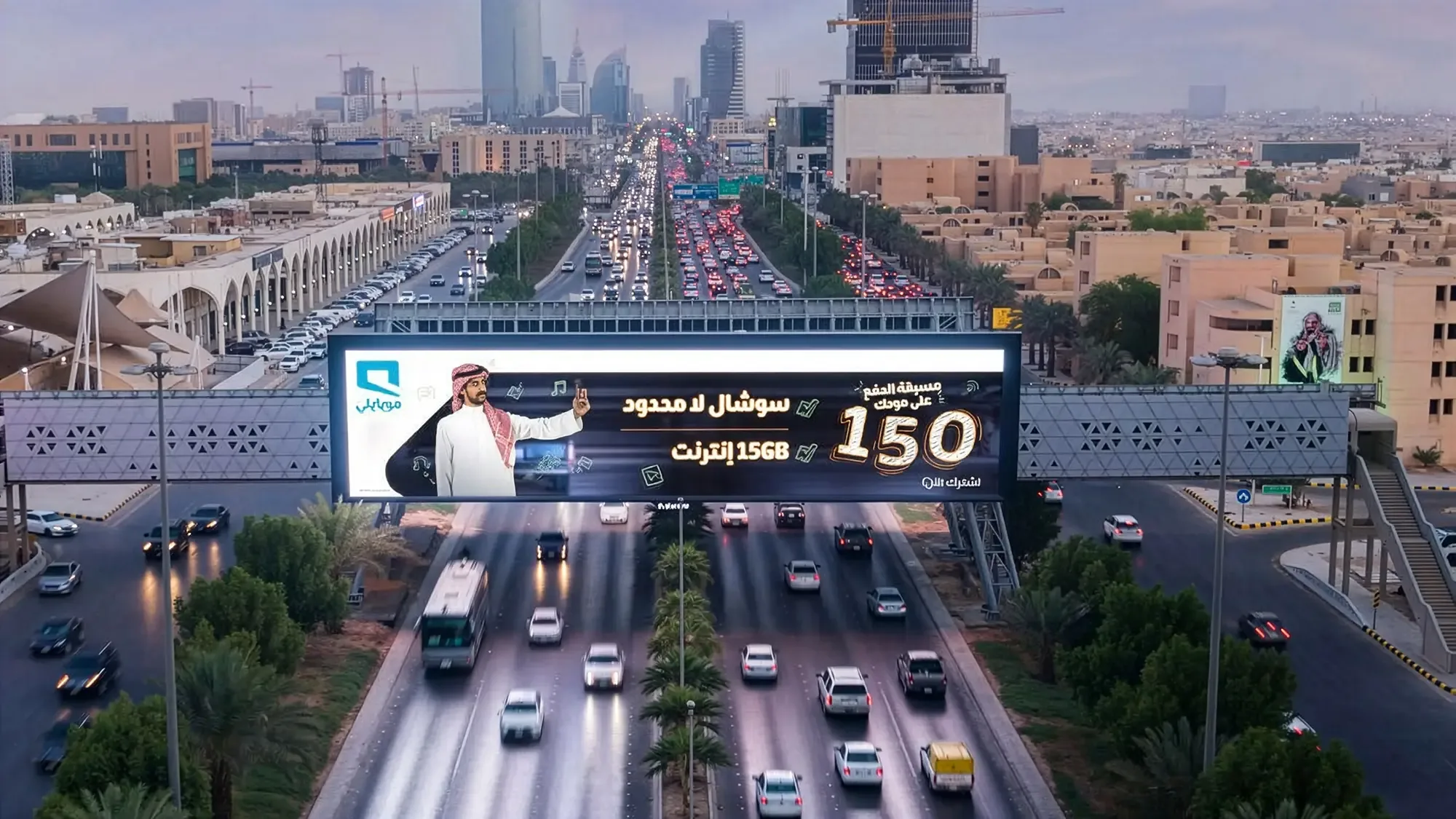 Bridge banner advertising in Riyadh, Saudi Arabia: a Mobily billboard crosses a busy multi-lane highway, with traffic underneath and towers ahead.