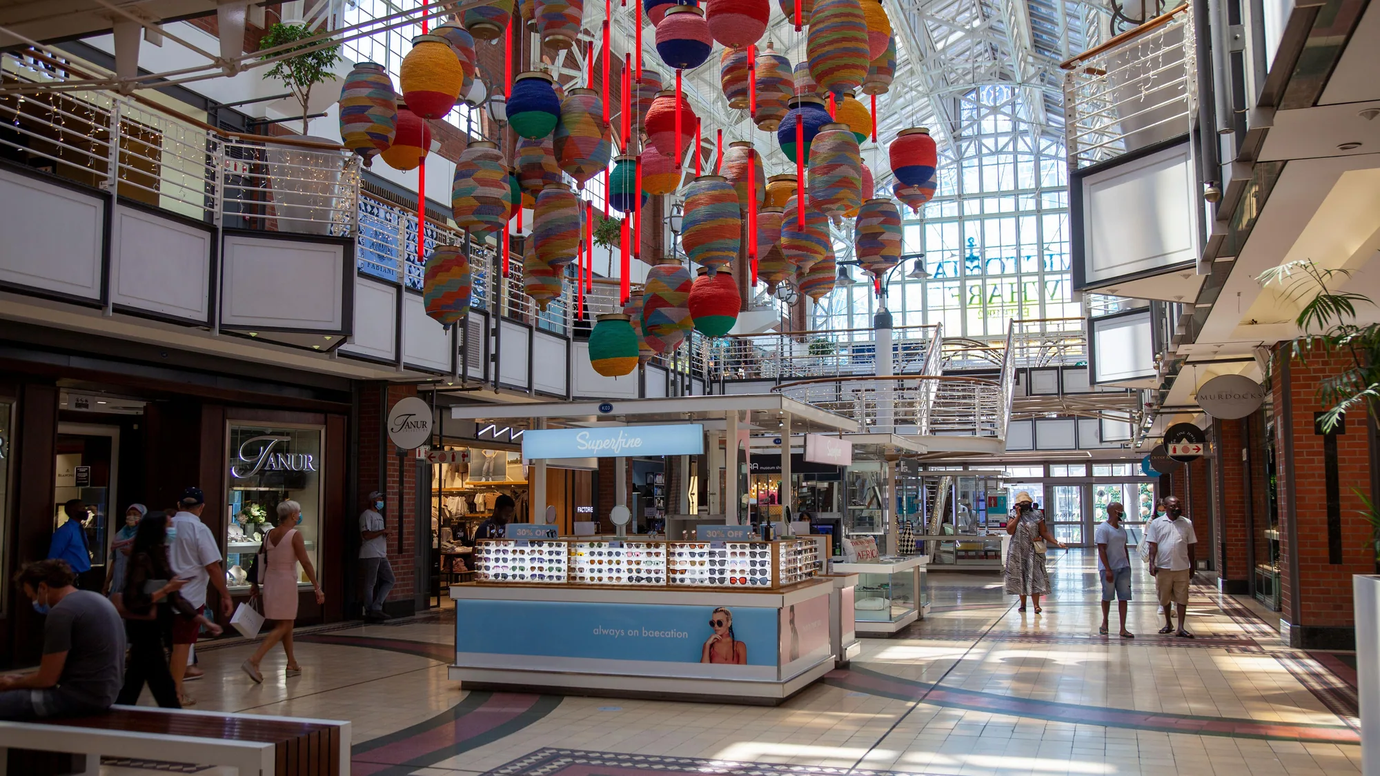 Mall advertising: vintage racing cars sit in a shopping atrium under hanging phone and watch banners, with an Into Africa shop below.