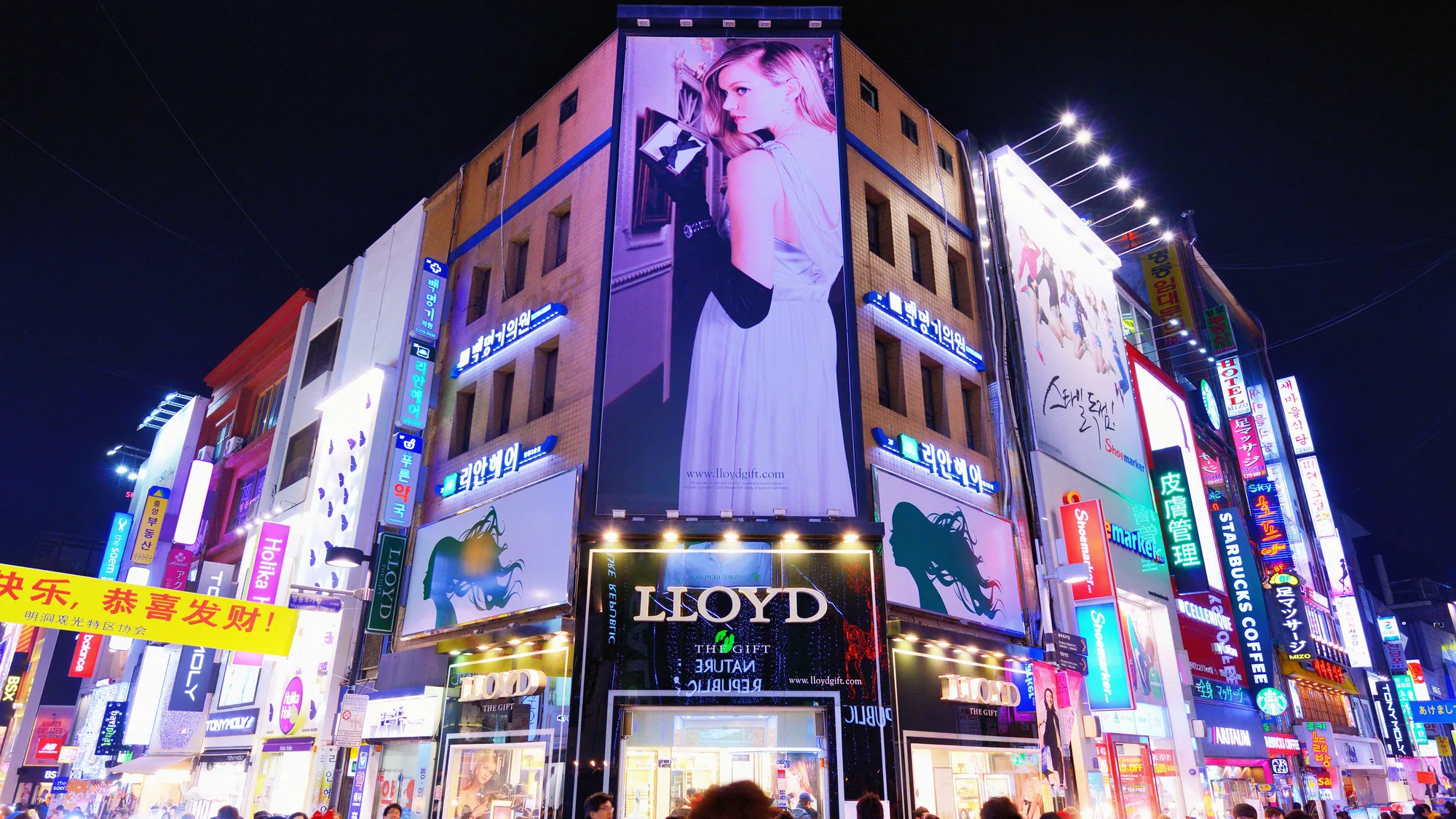 Building wrap advertising in Myeongdong, Seoul: a Lloyd storefront in a large fashion portrait lights a crowded night street.