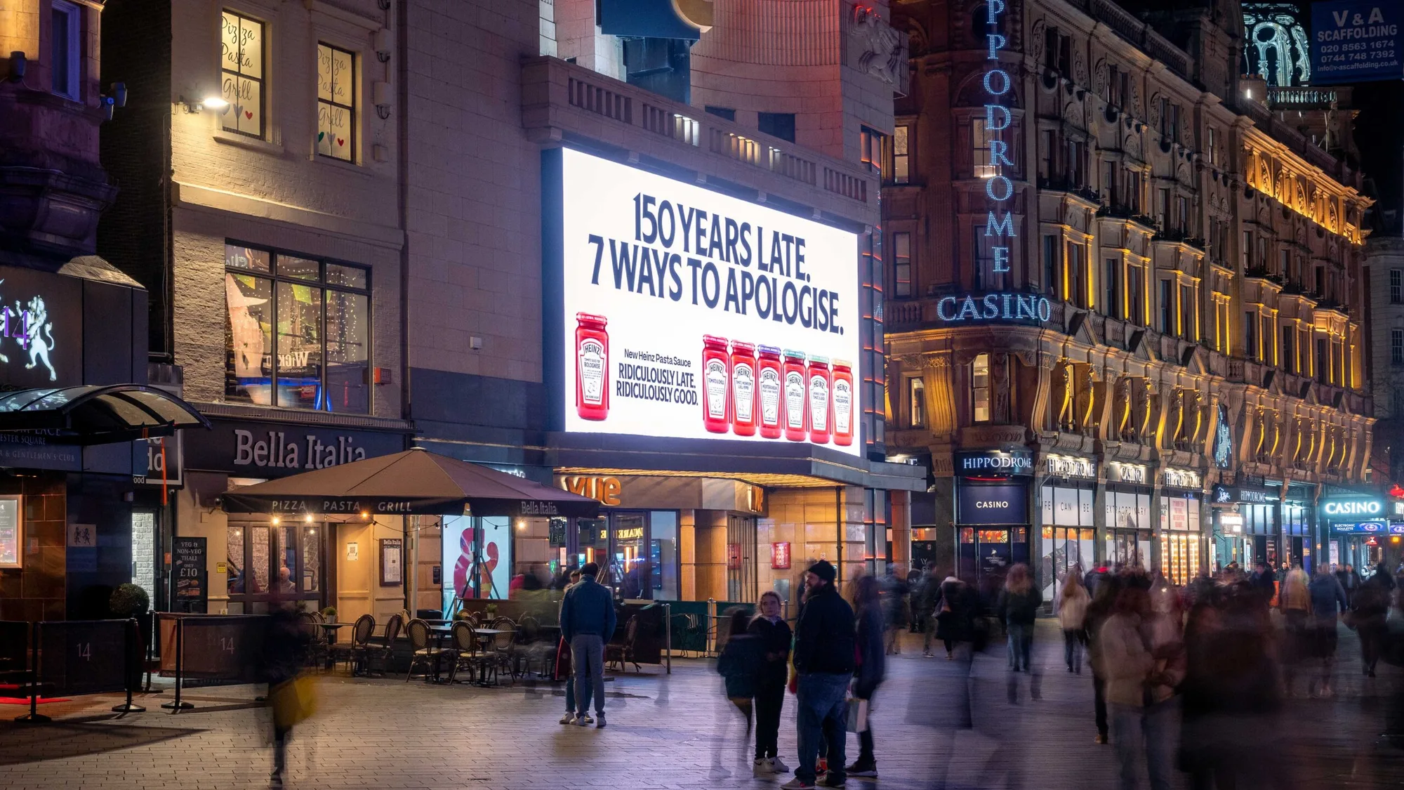Billboard advertising in Leicester Square, London: a Heinz screen reading 150 years late, 7 ways to apologise sits above Bella Italia, beside the Hippodrome Casino.