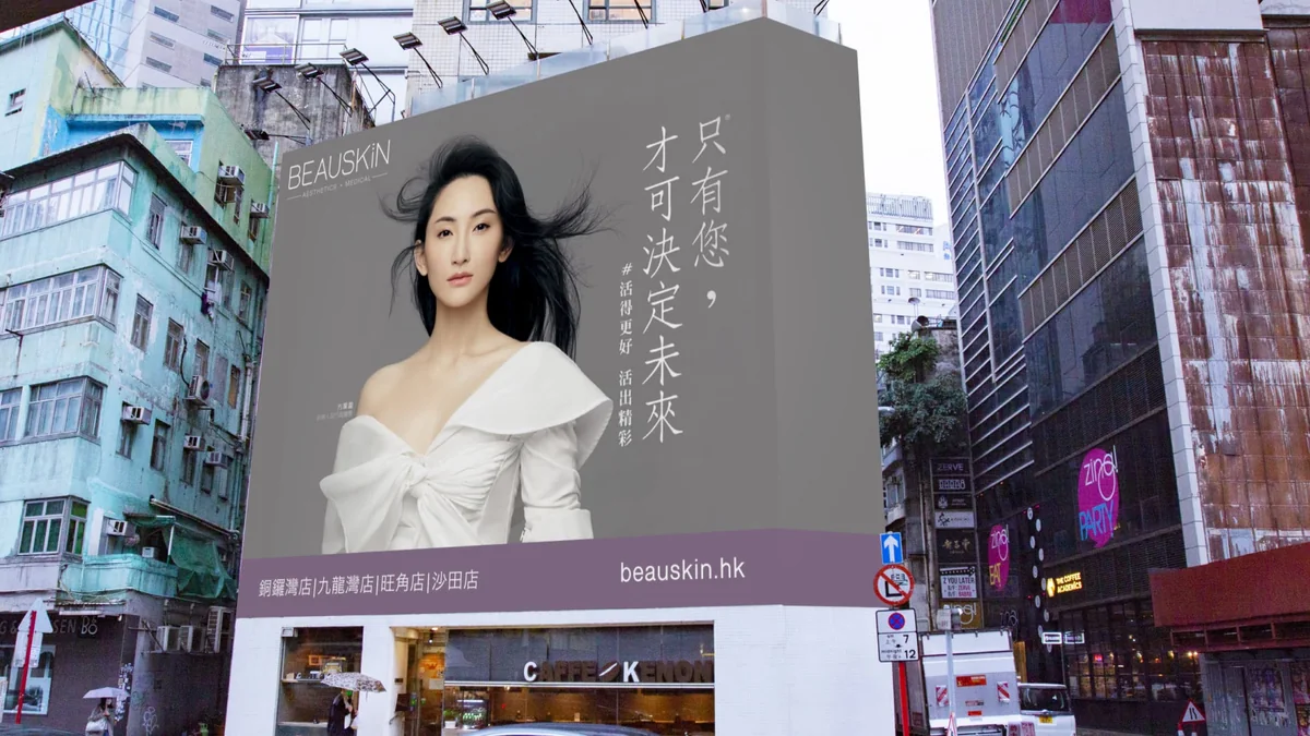 Large format wall banner advertising in Hong Kong: a Beauskin banner of a woman in a white top stands among high-rise streets.