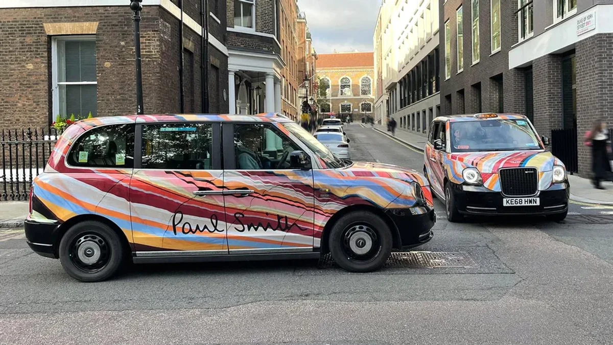 Taxi wrap advertising in London, in the United Kingdom: two taxis wear a colourful Paul Smith wrap on a city street.