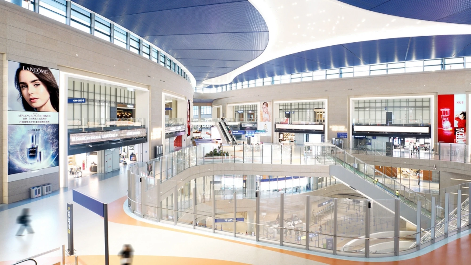 Airport advertising at Shanghai Pudong Airport in China: Lancôme posters hang in the multi-level hall above shops, escalators and a curved blue ceiling.